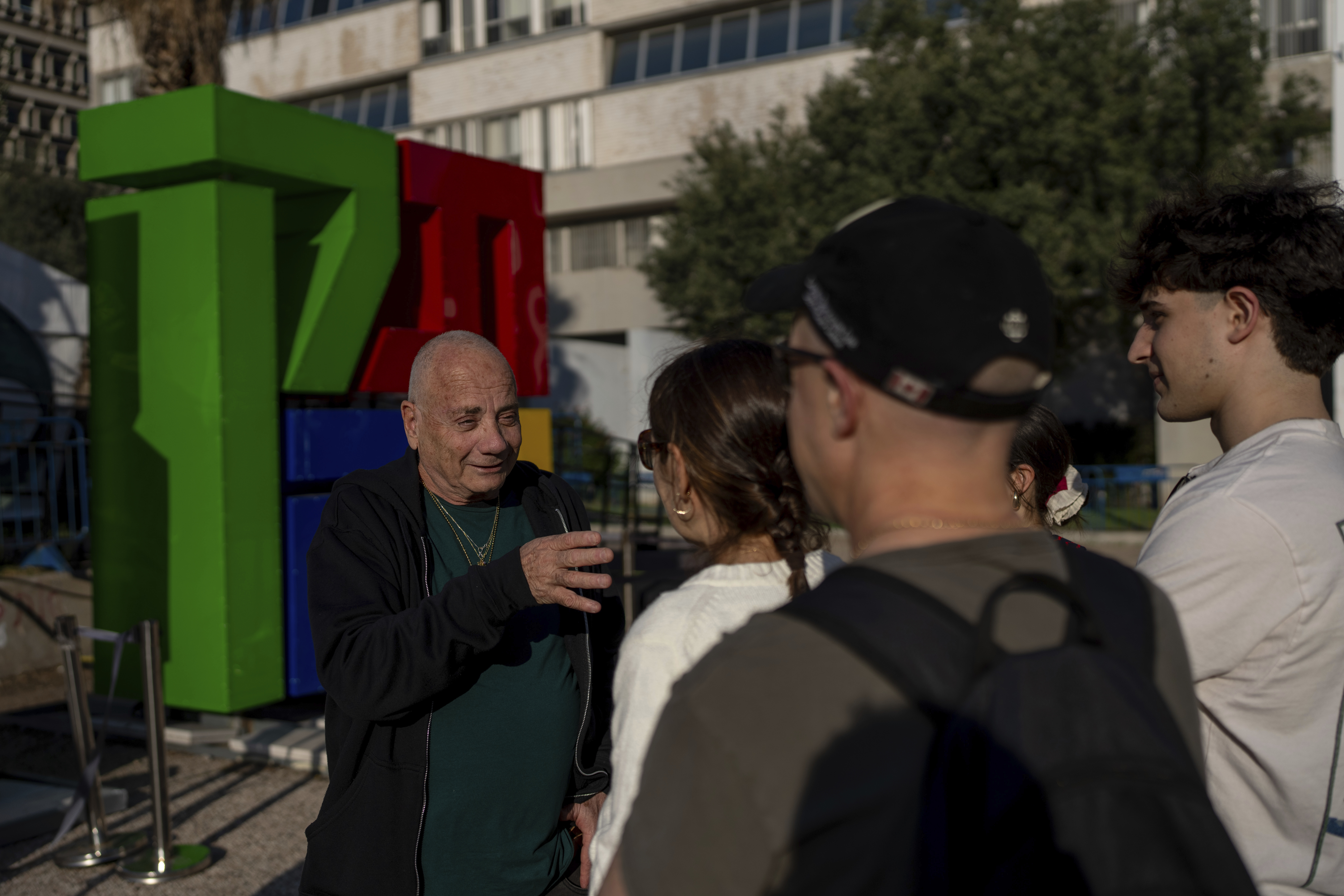 Luis Har, who was rescued from Hamas captivity in an Israeli raid last year, talks with visitors to the Hostages Square in Tel Aviv, Israel, Monday, Jan. 6, 2025. (AP Photo/Ohad Zwigenberg)