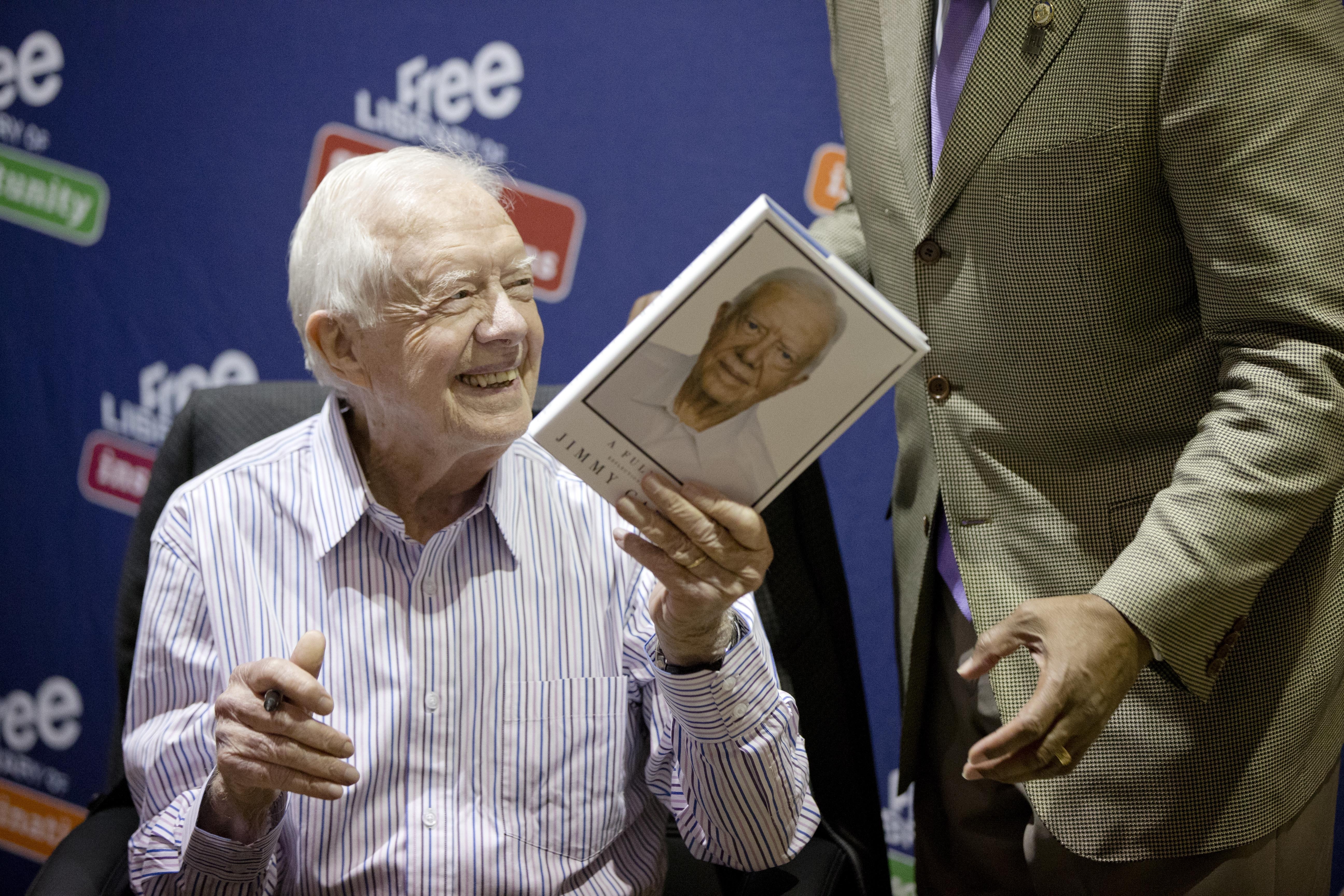 FILE - Former President Jimmy Carter hands a copy of his new book, "A Full Life: Reflections at Ninety," to Philadelphia Mayor Michael Nutter, on July 10, 2015, at the Free Library in Philadelphia. (AP Photo/Matt Rourke, File)