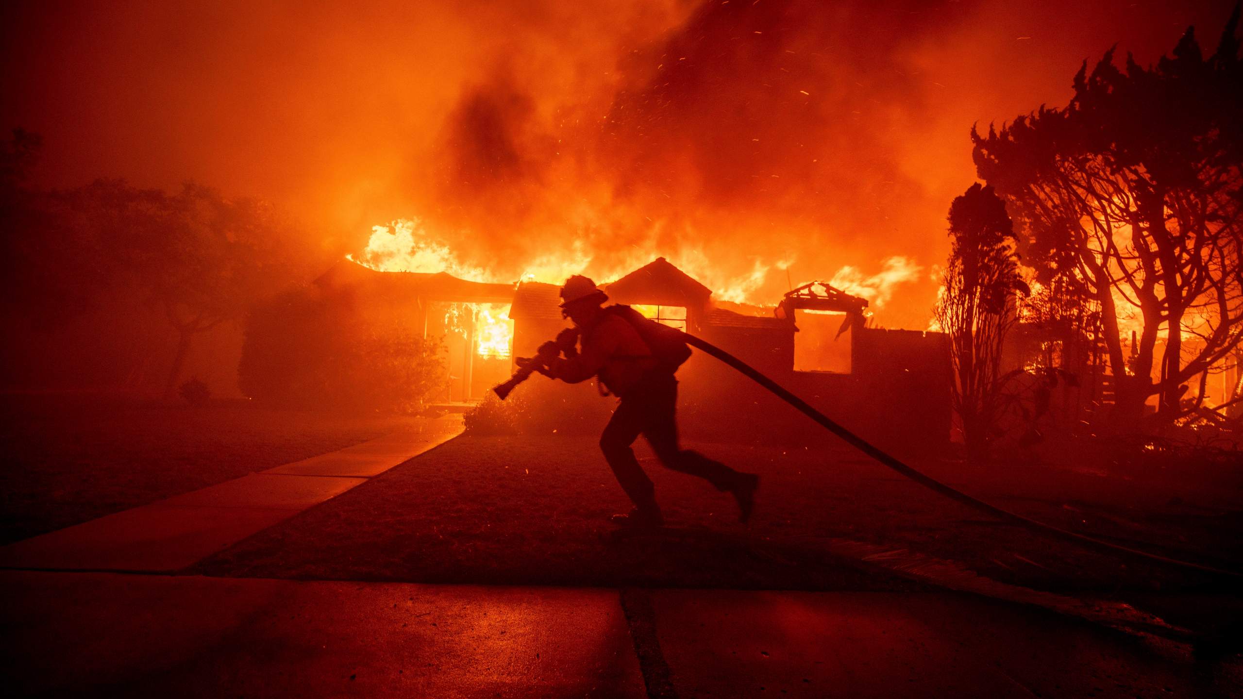 A firefighter battles the Palisades Fire as it burns a structure in the Pacific Palisades neighborhood of Los Angeles, Tuesday, Jan. 7, 2025. (AP Photo/Ethan Swope)