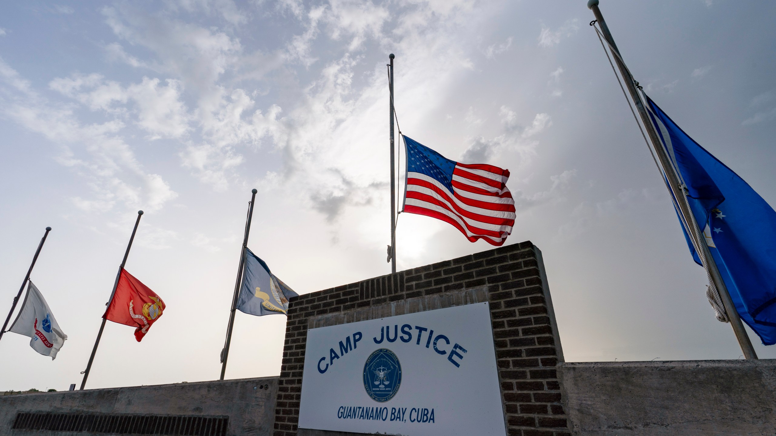 FILE - In this photo reviewed by U.S. military officials, flags fly at half-staff at Camp Justice, Aug. 29, 2021, in Guantanamo Bay Naval Base, Cuba. (AP Photo/Alex Brandon, File)