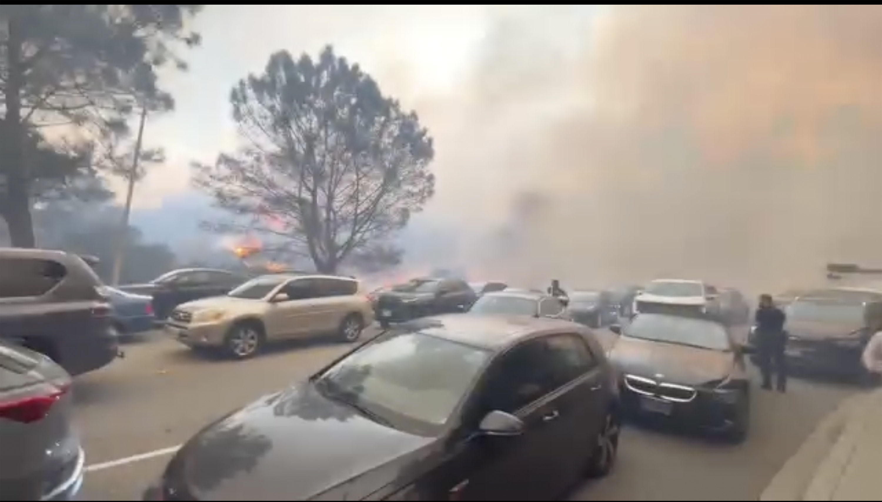 CORRECTS LOCATION TO PACIFIC PALISADES, INSTEAD OF GLENHAVEN - People evacuate their cars as flames from a wildfire spread to the street near Pacific Palisades, Calif., on Tuesday, Jan. 7, 2025. (Aaron Samson via AP)