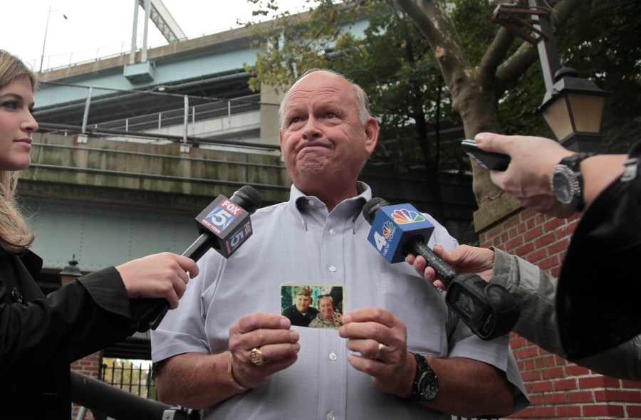 FILE - Ken Fairben holds a photo showing his son Keith, left, a victim of the Sept, 11, attacks, as he talks with reporters Oct. 15, 2012, outside Fort Hamilton Army base in Brooklyn, N.Y. (AP Photo/Bebeto Matthews, File)