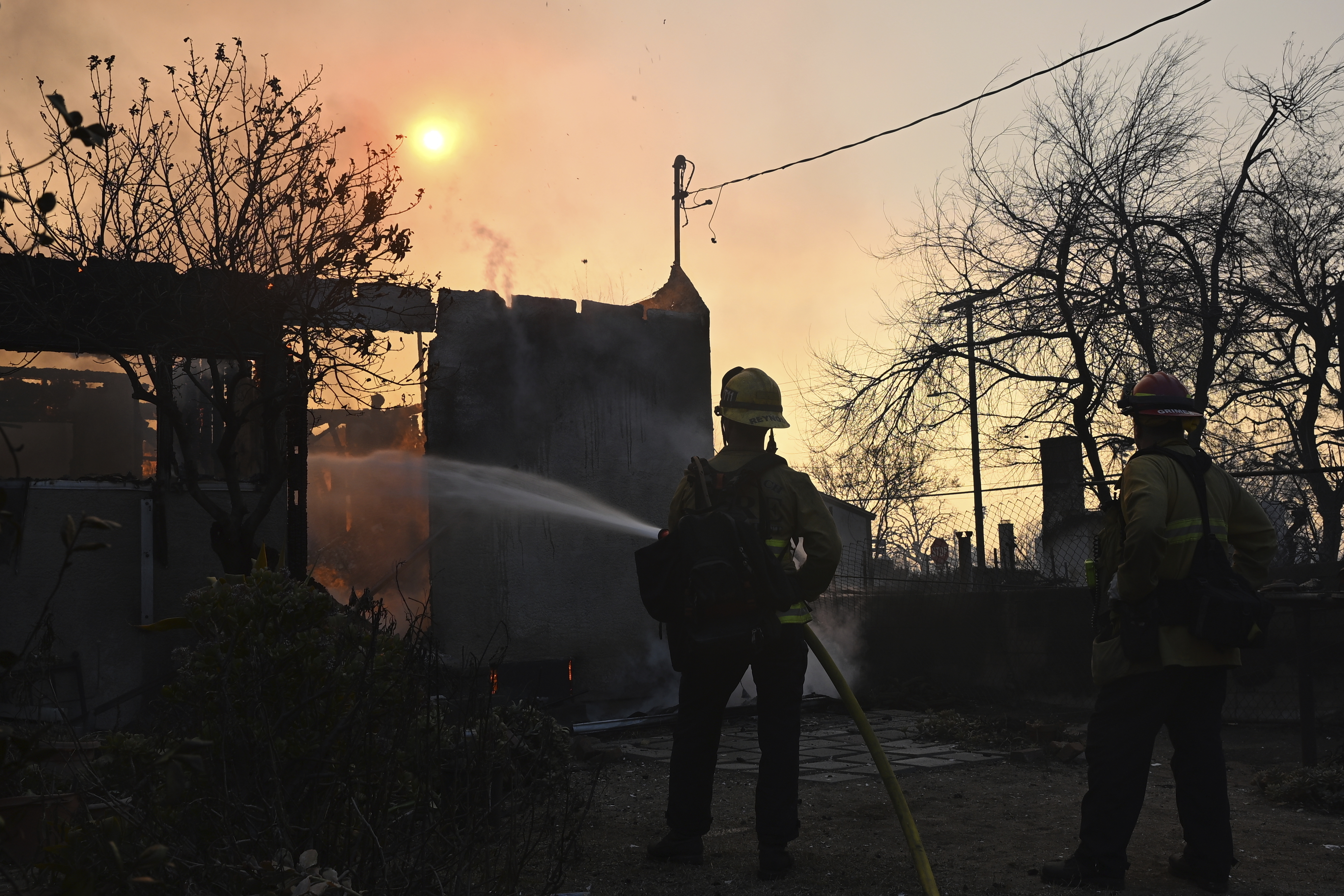 Firefighters water down a home after the Eaton Fire burns in Altadena, Calif., Thursday, Jan. 9, 2025. (AP Photo/Nic Coury)