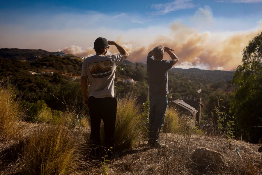 Topanga Canyon inhabitants look on as the Palisades Fire burns in the hills between Pacific Palisades and Malibu Wednesday, Jan. 8, 2025 in Topanga, Calif. (AP Photo/Etienne Laurent)