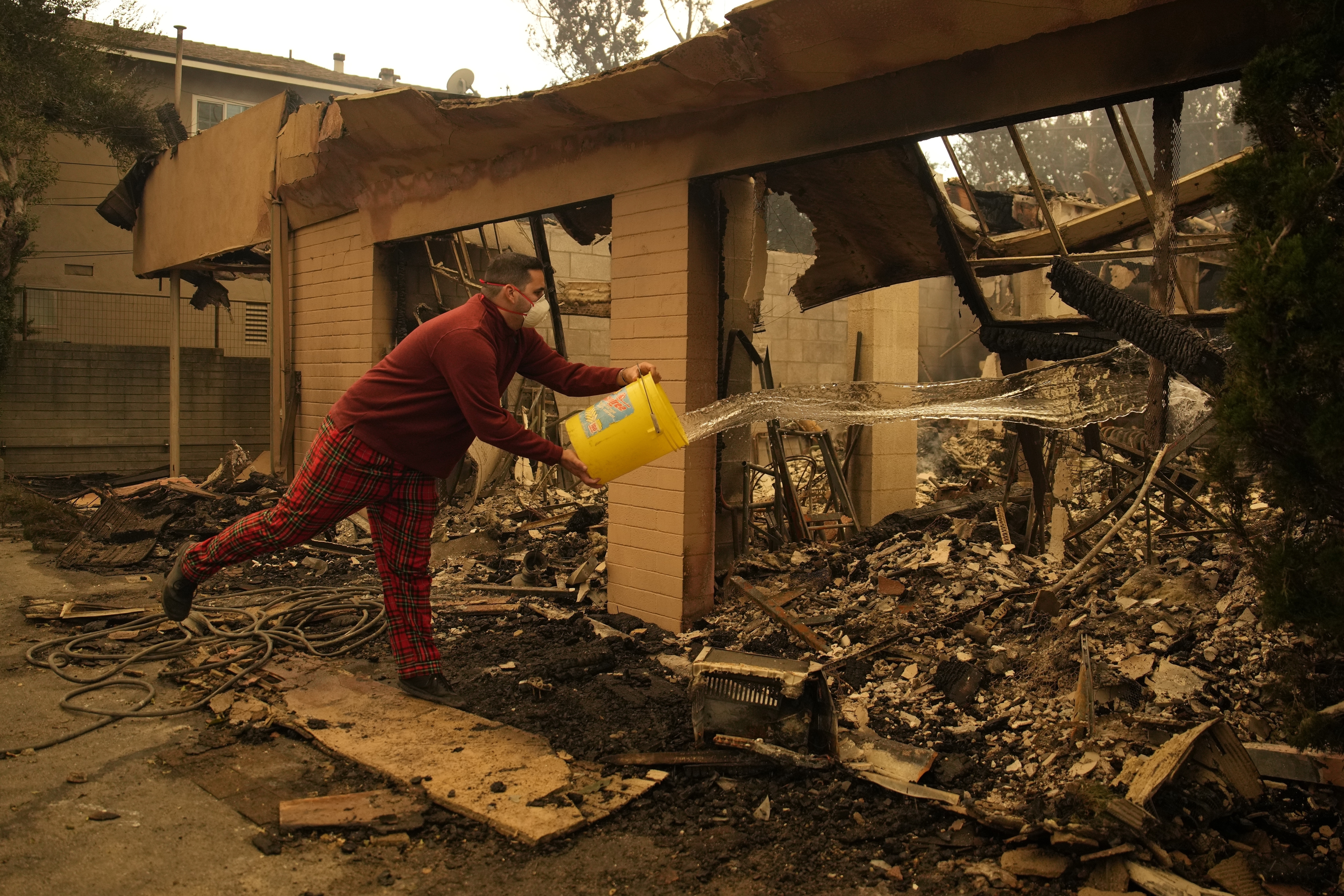 Shane Torre douses hot spots of what remains of his home In Altadena, Calif., Thursday, Jan. 9, 2025. (AP Photo/John Locher)