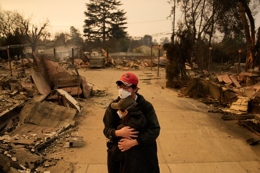 Ari Rivera, rear, Anderson Hao hold each other in front of their destroyed home in Altadena, Calif., Thursday, Jan. 9, 2025. (AP Photo/John Locher)