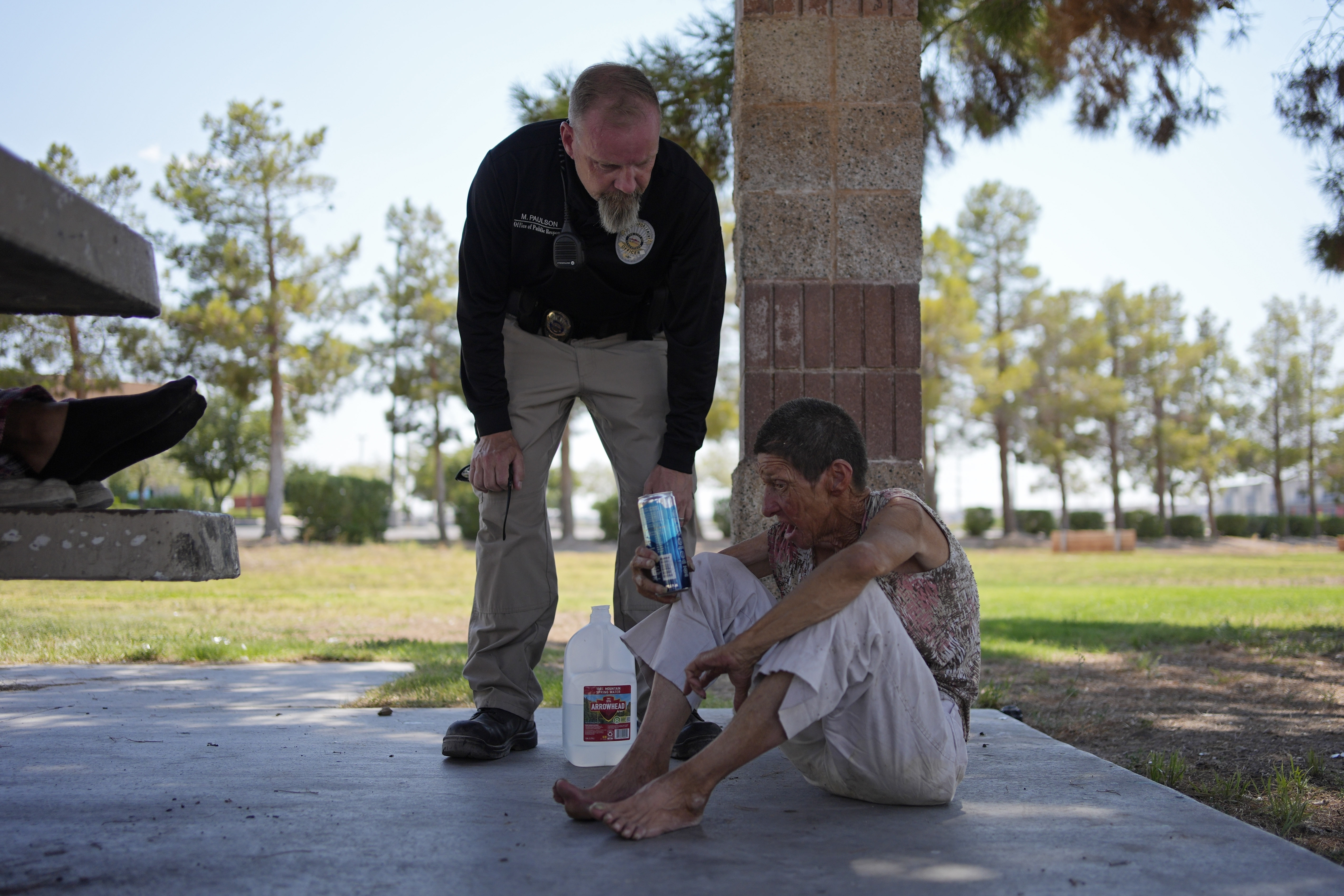 FILE - Mark Paulson, a Public Response and Code Enforcement officer, checks on Deb Billet, 66, before calling an ambulance to take her to a hospital for heat-related symptoms, July 10, 2024, in Henderson, Nev. (AP Photo/John Locher, File)