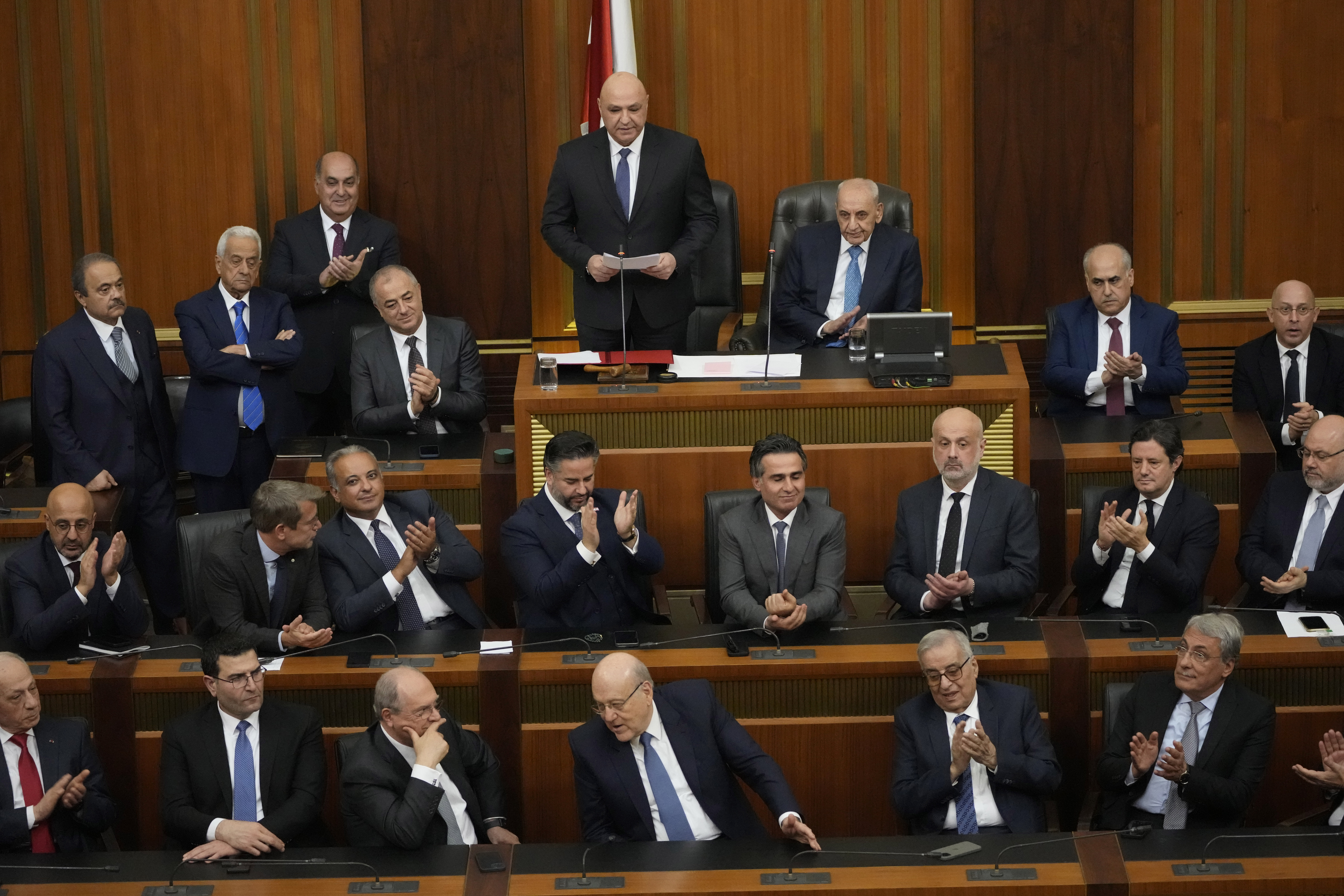 Lebanese cabinet ministers applaud the newly-elected Lebanese President Joseph Aoun, standing at the top, as gives his first speech at Parliament after being sworn in as president in Beirut, Lebanon, Thursday, Jan. 9, 2025.(AP Photo/Hussein Malla)