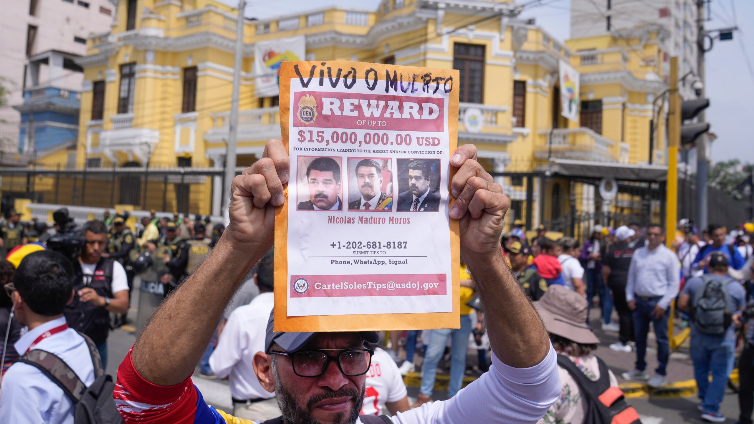 Venezuelan Tulio Rodriguez holds a wanted sign of Venezuelan President Nicolas Maduro that reads in Spanish: "Reward. Dead or alive" outside the Venezuelan embassy in Lima, Peru, Thursday, Jan. 9, 2025, the day before his inauguration for a third term. (AP Photo/Martin Mejia)