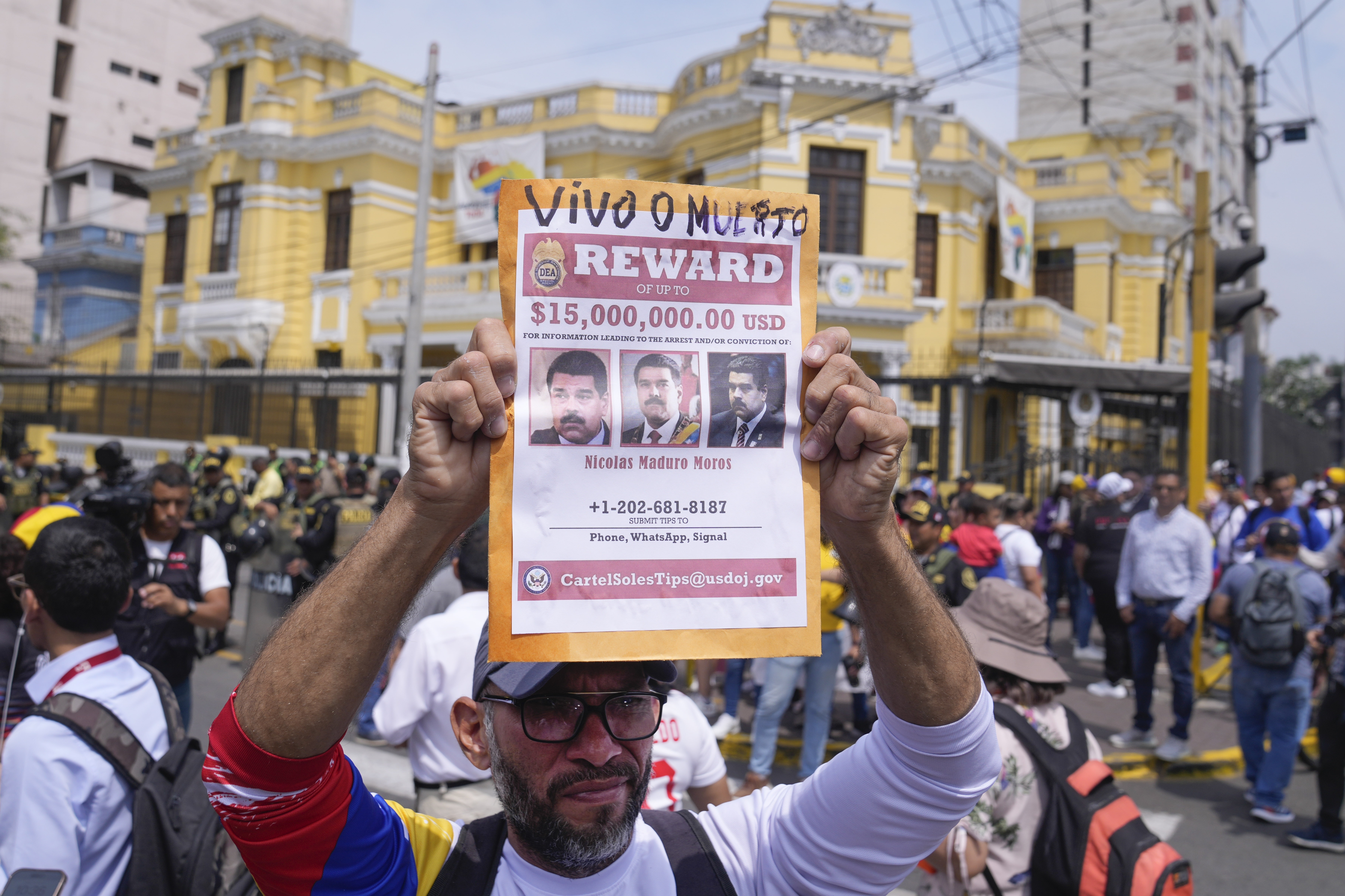 Venezuelan Tulio Rodriguez holds a wanted sign of Venezuelan President Nicolas Maduro that reads in Spanish: "Reward. Dead or alive" outside the Venezuelan embassy in Lima, Peru, Thursday, Jan. 9, 2025, the day before his inauguration for a third term. (AP Photo/Martin Mejia)