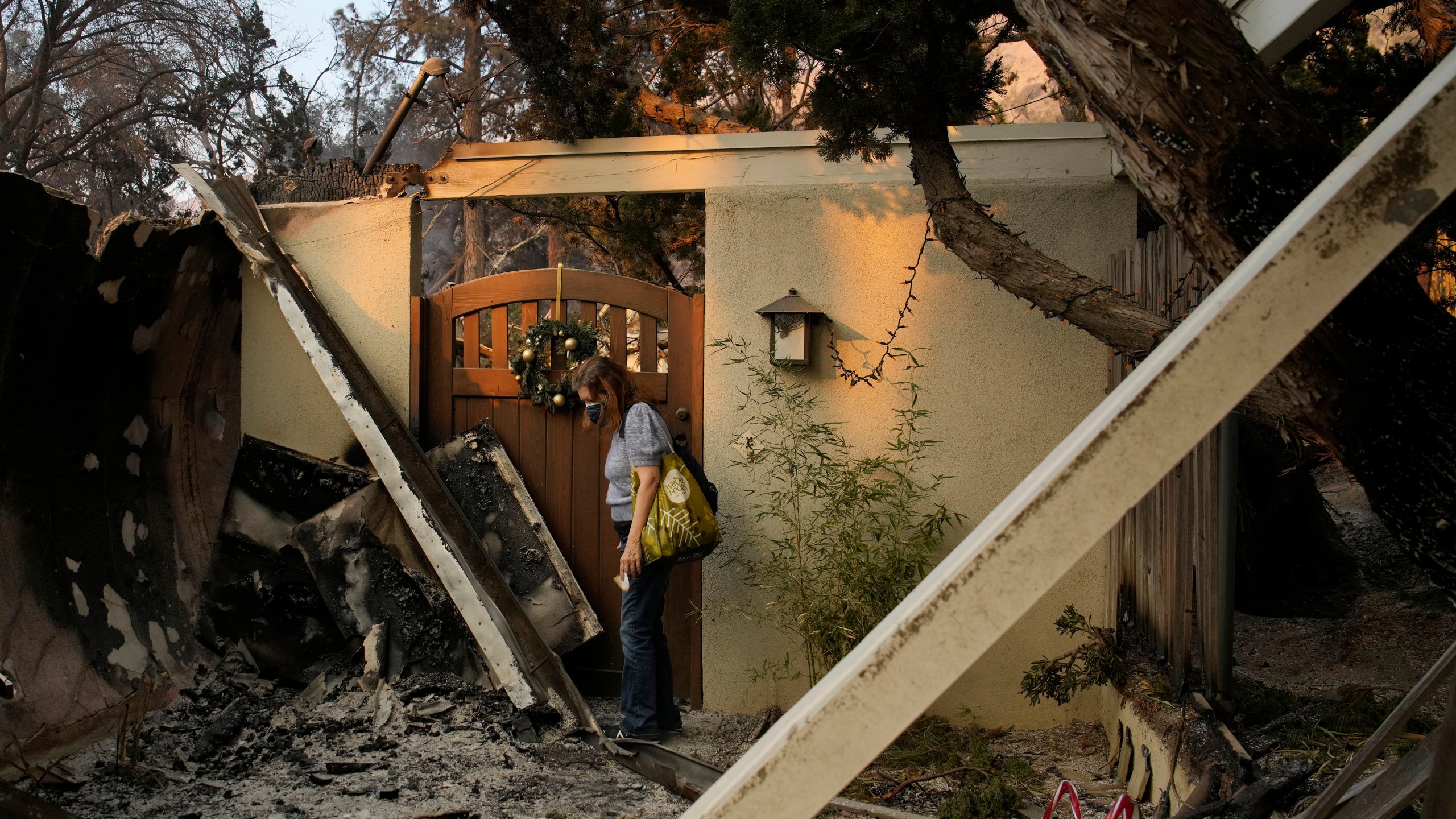 Glenda, who declined to give her last name, stands near the entrance of her home destroyed by the Eaton fire Thursday, Jan. 9, 2025, in Altadena, Calif. (AP Photo/John Locher)