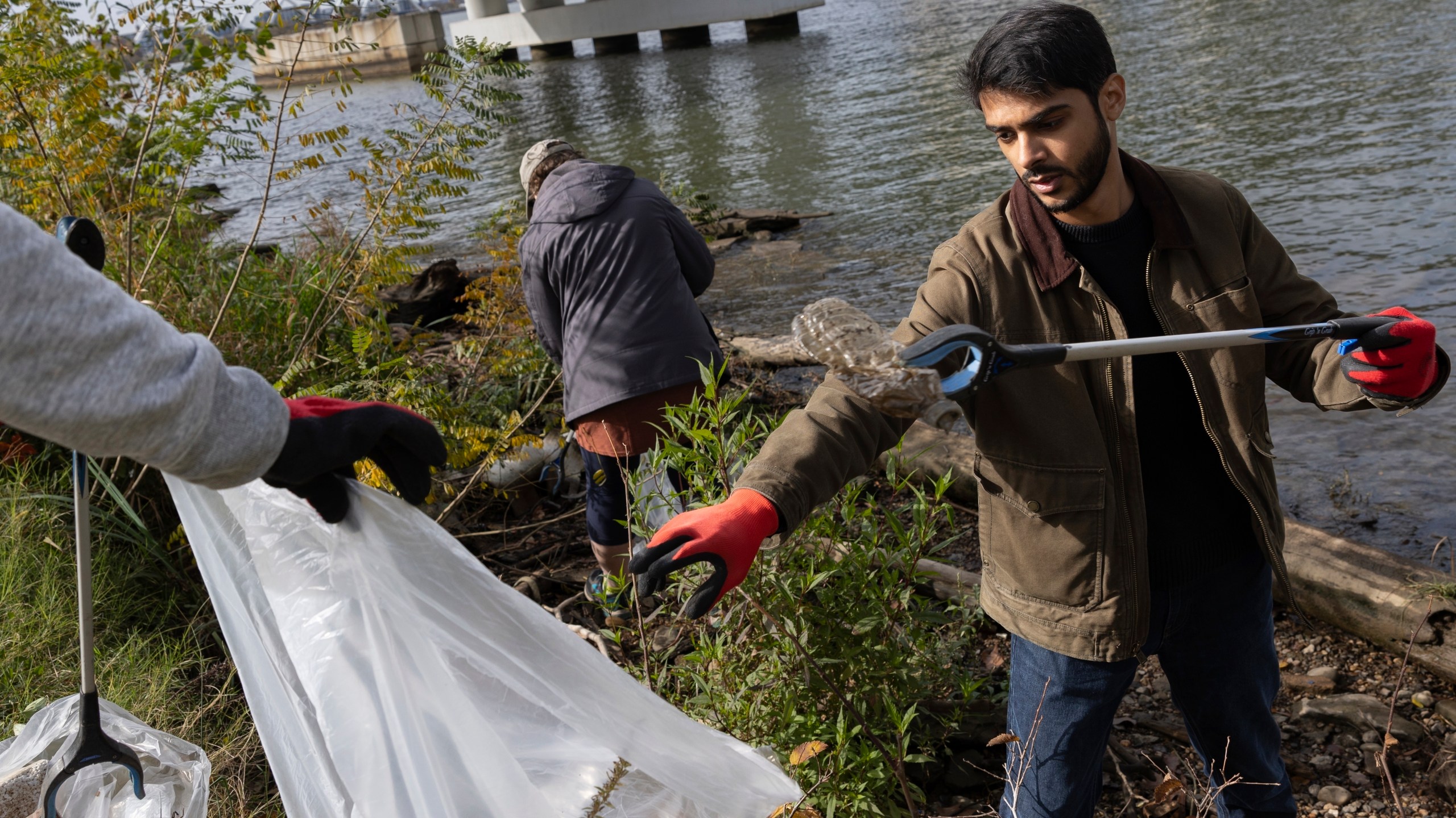 FILE - Volunteers collect trash items during a park cleanup on Nov. 15, 2023, at Anacostia Park in Washington. (AP Photo/Tom Brenner, File)