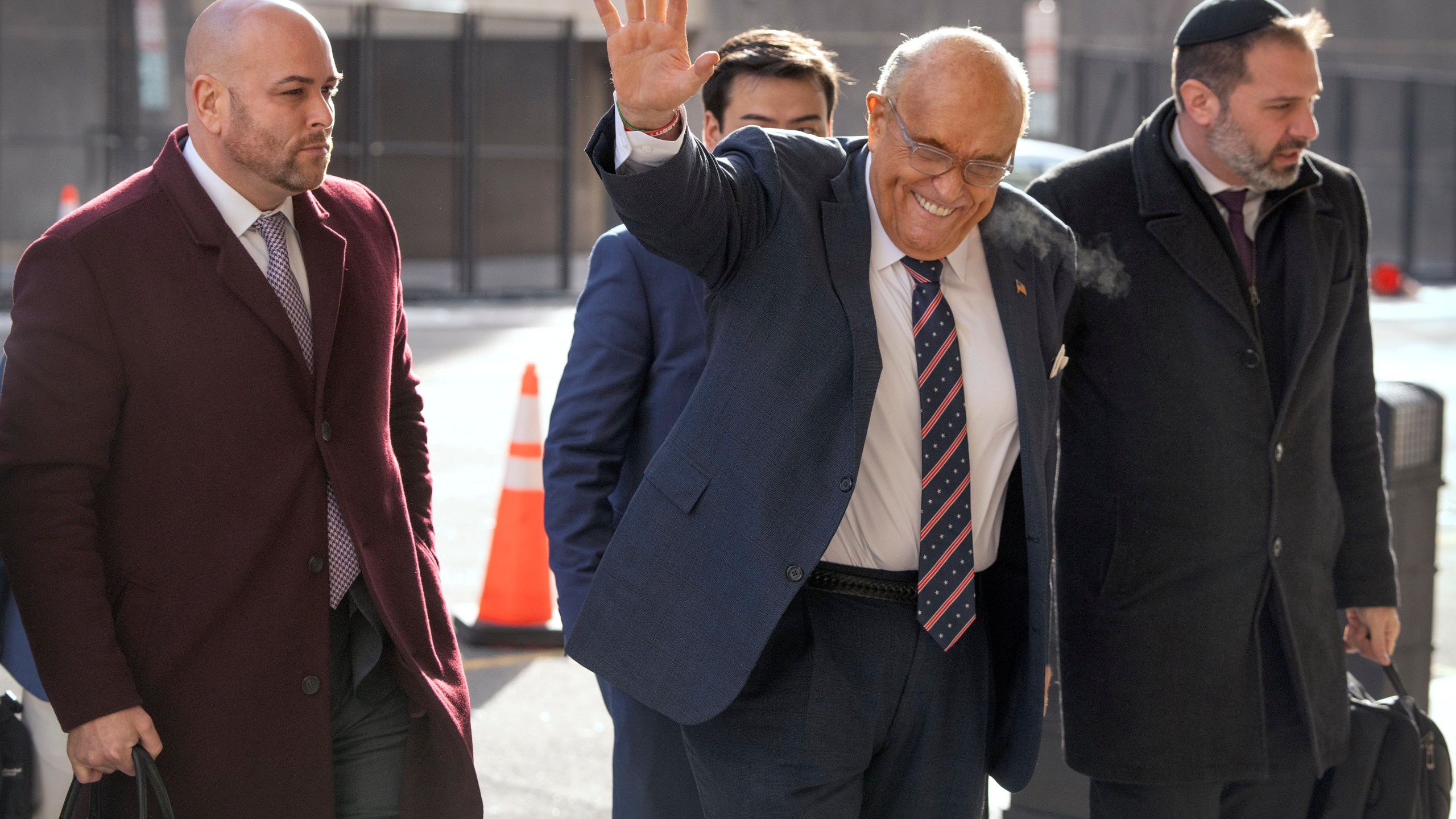 Rudy Giuliani, second from right, waves as he arrives at federal court in Washington, Friday, Jan. 10, 2025. (AP Photo/Mark Schiefelbein)