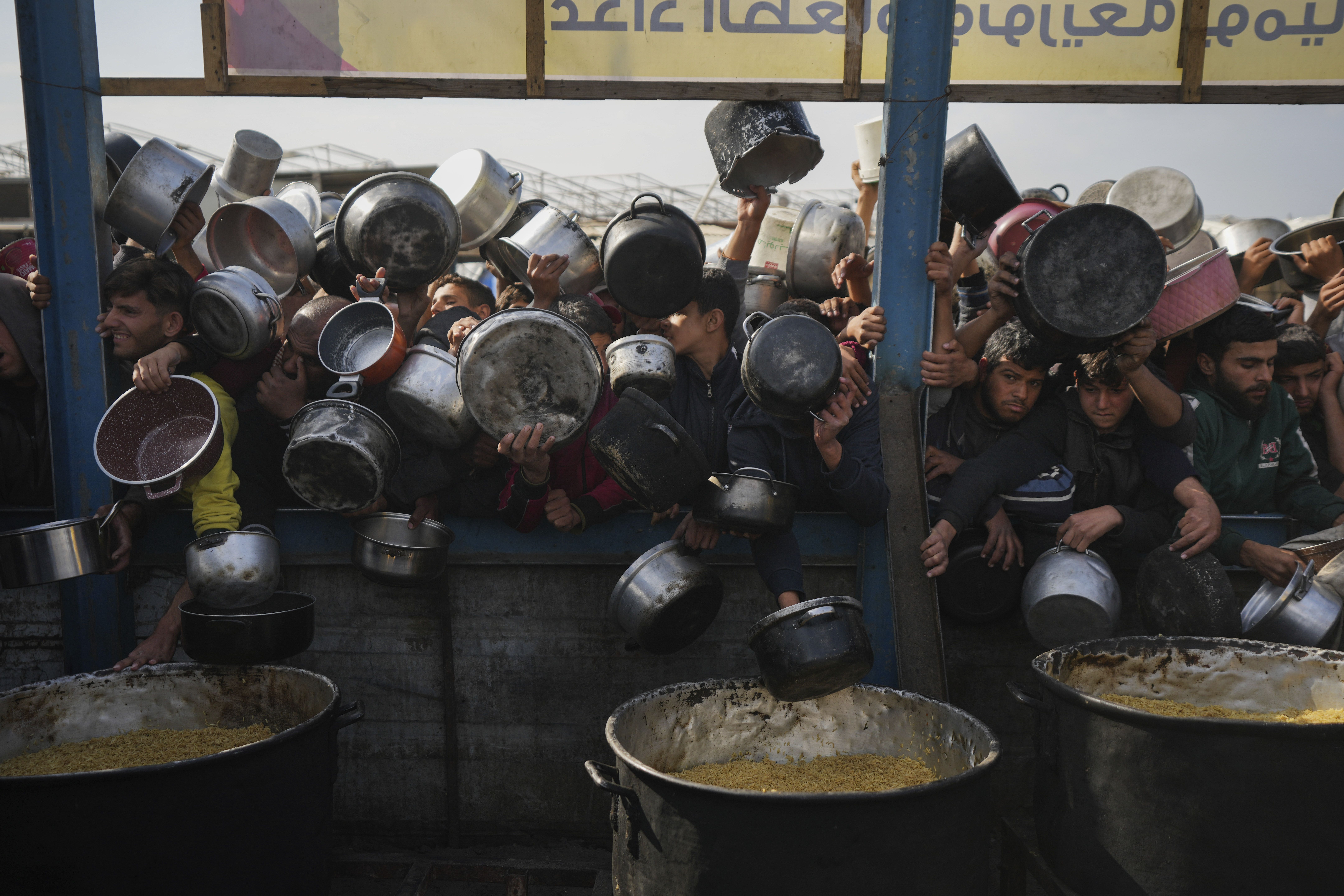 Palestinians struggle to reach for food at a distribution center in Khan Younis, Gaza Strip, Friday, Jan. 9, 2025. (AP Photo/Abdel Kareem Hana)