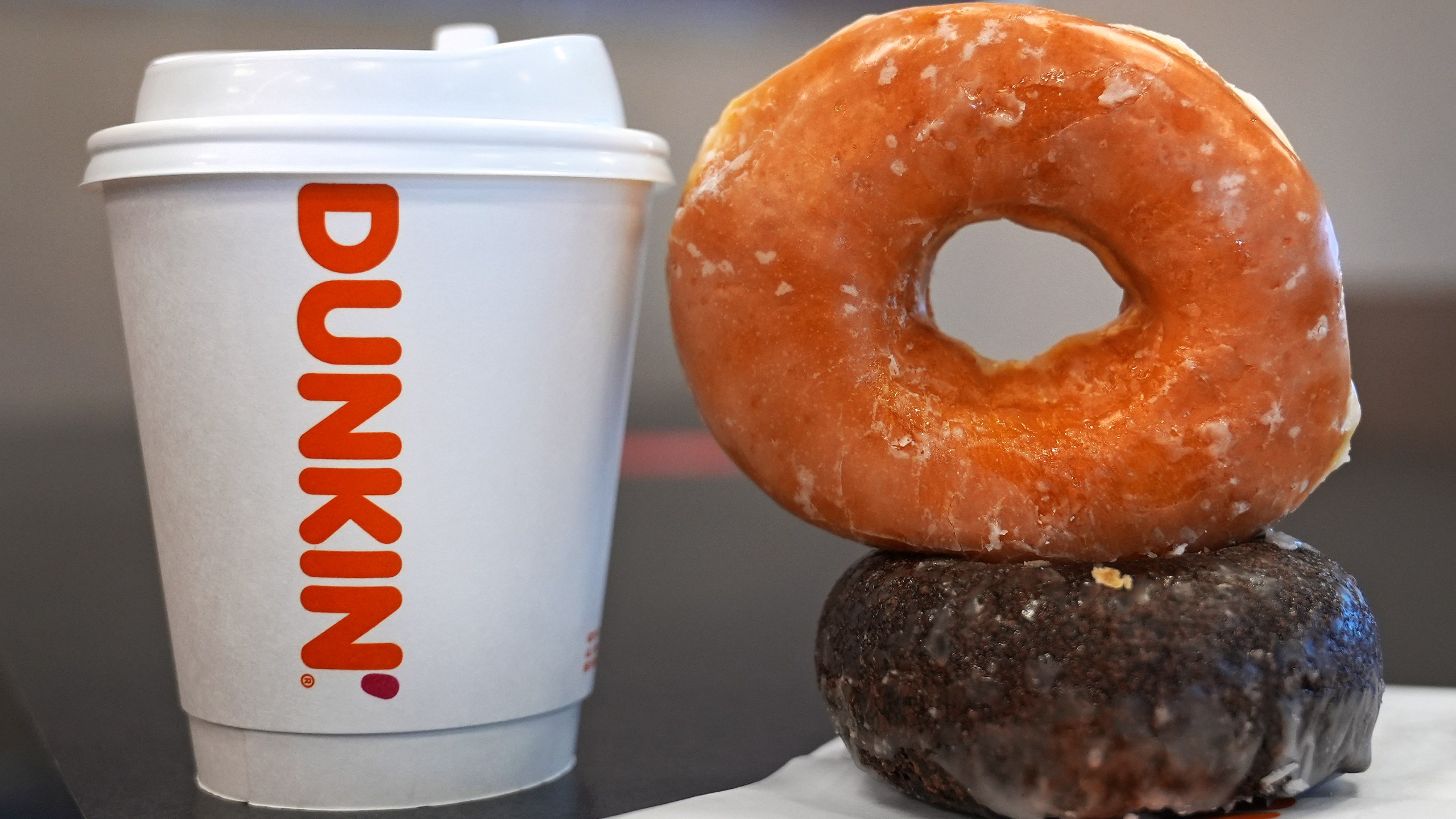 Two donuts and a cup of coffee rest on a counter at a Dunkin' location, Friday, Jan. 10, 2025, in Derry, N.H. (AP Photo/Charles Krupa)