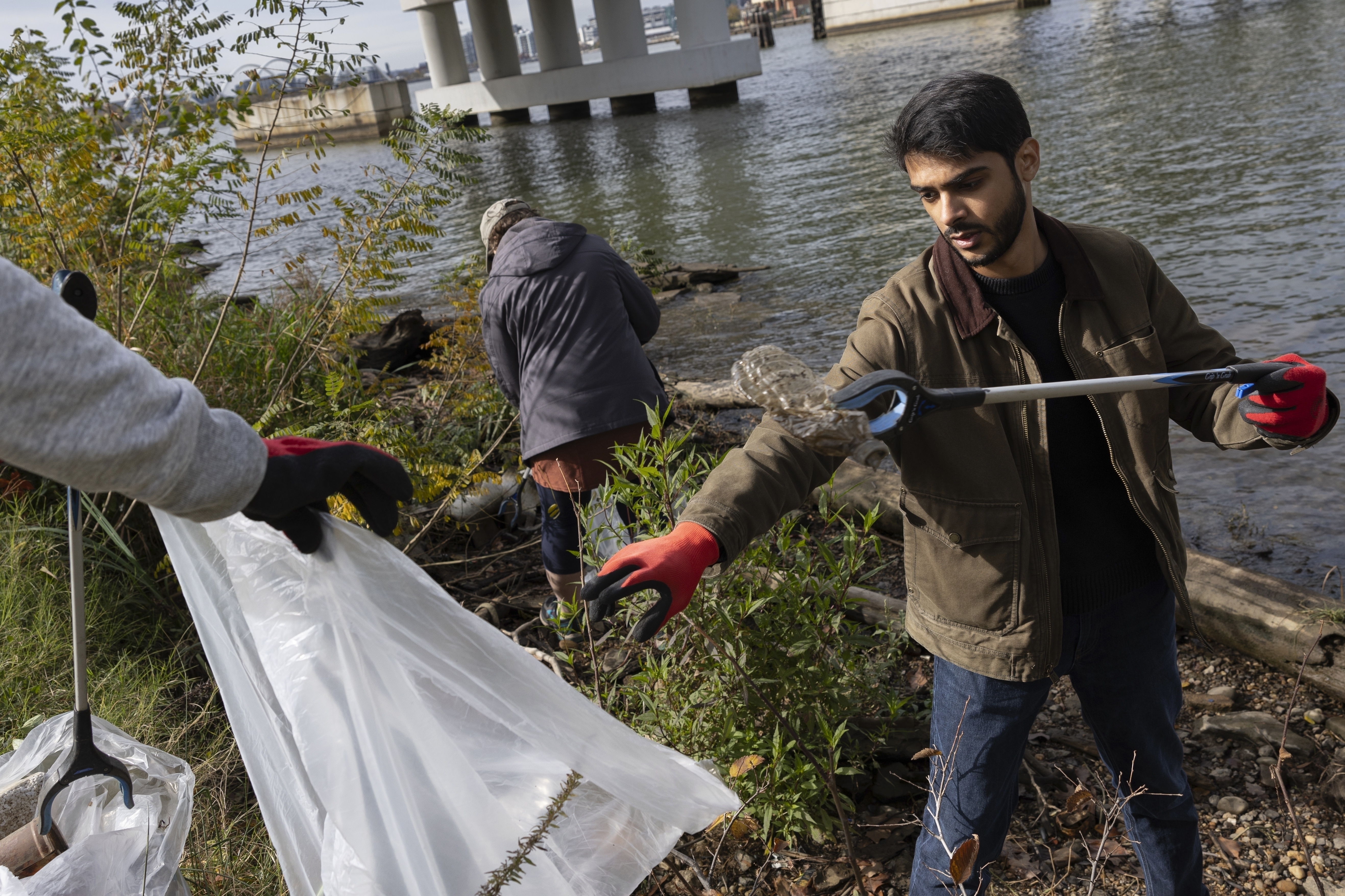 FILE - Volunteers collect trash items during a park cleanup on Nov. 15, 2023, at Anacostia Park in Washington. (AP Photo/Tom Brenner, File)