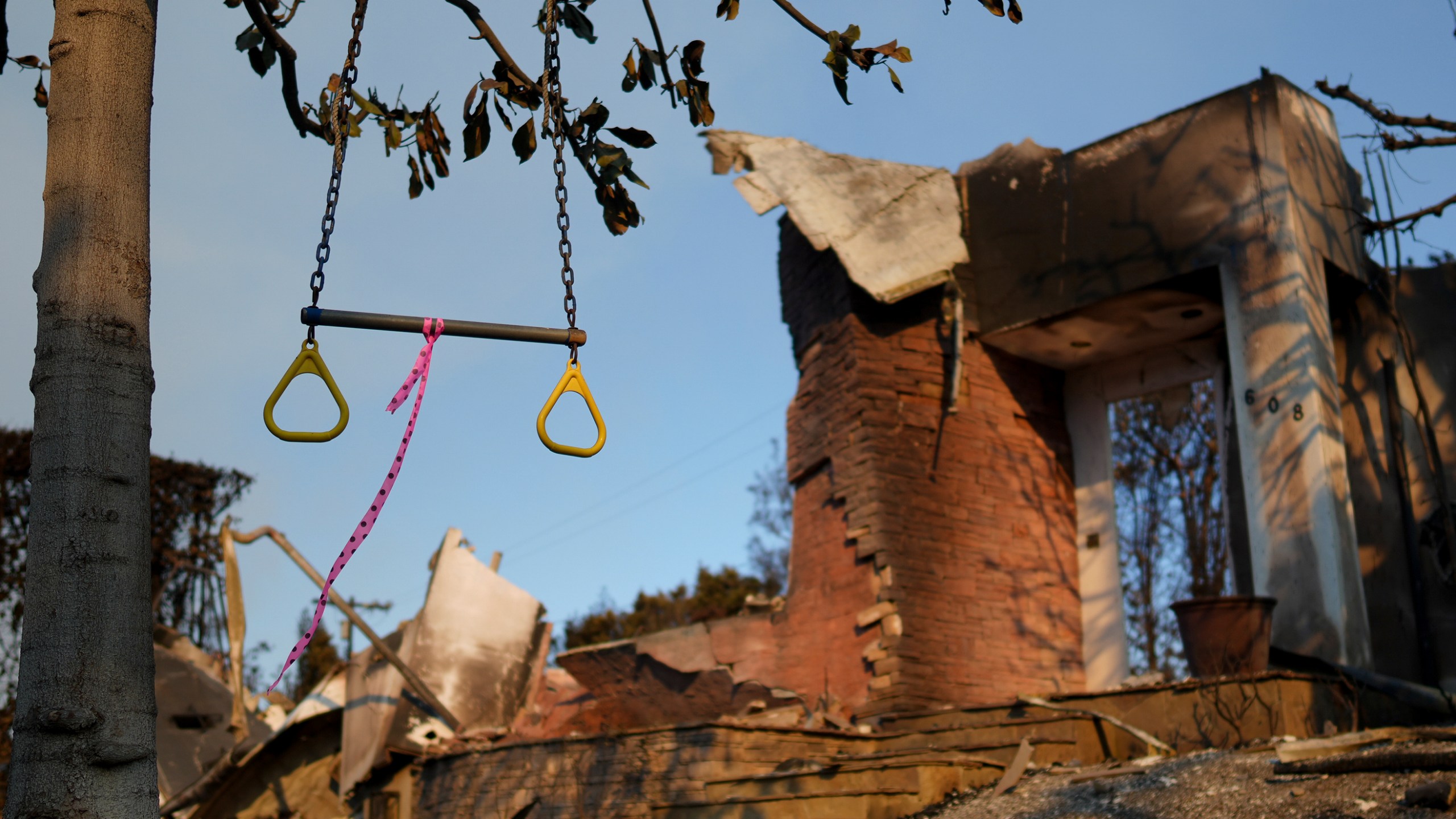 A swing hangs from a tree in front of a fire-damaged residence in the aftermath of the Palisades Fire in the Pacific Palisades neighborhood of Los Angeles, Friday, Jan. 10, 2025. (AP Photo/Eric Thayer)