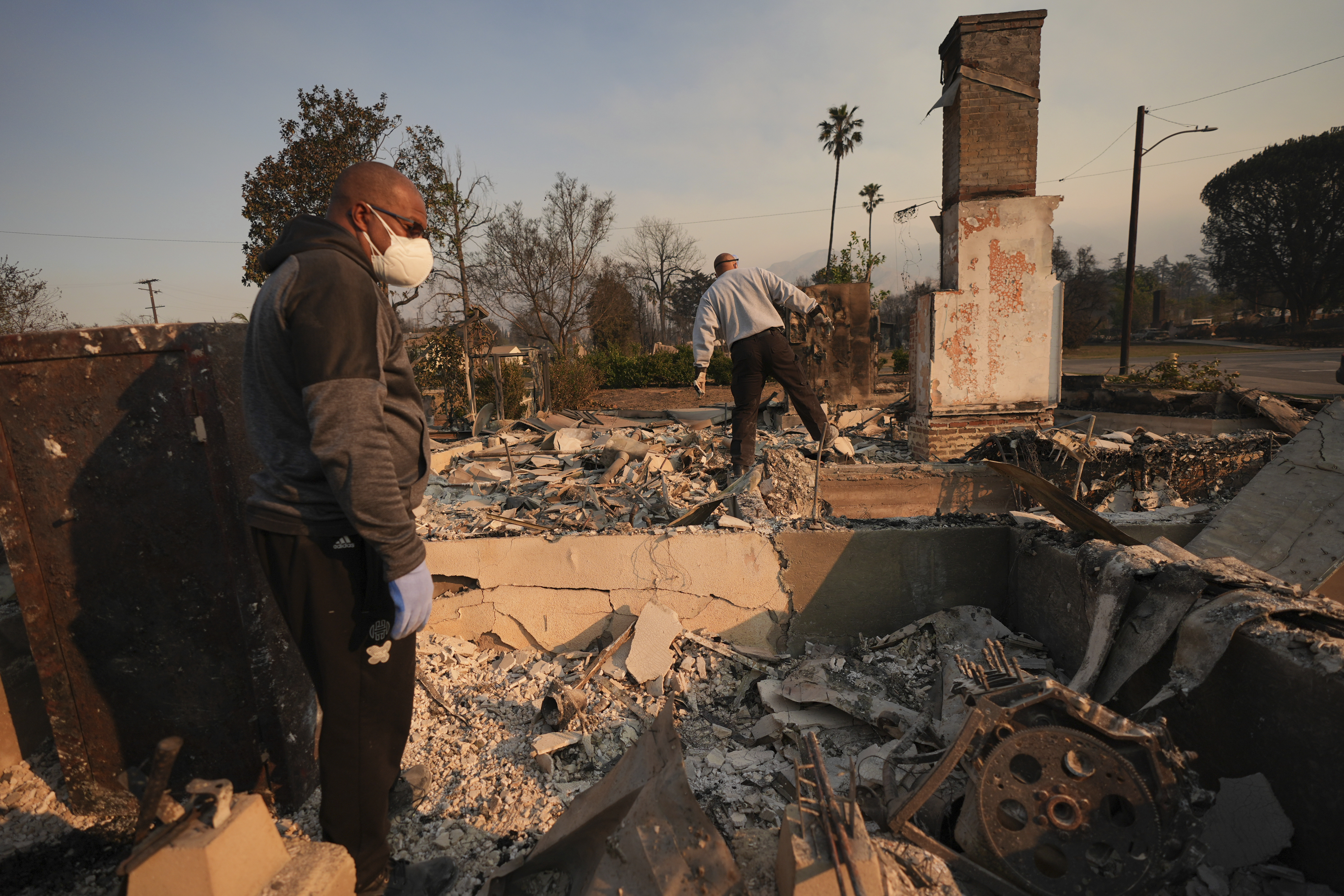 Kenneth Snowden, left, surveys the damage to his fire-ravaged property with his brother Ronnie in the aftermath of the Eaton Fire Friday, Jan. 10, 2025 in Altadena, Calif. (AP Photo/Jae C. Hong)