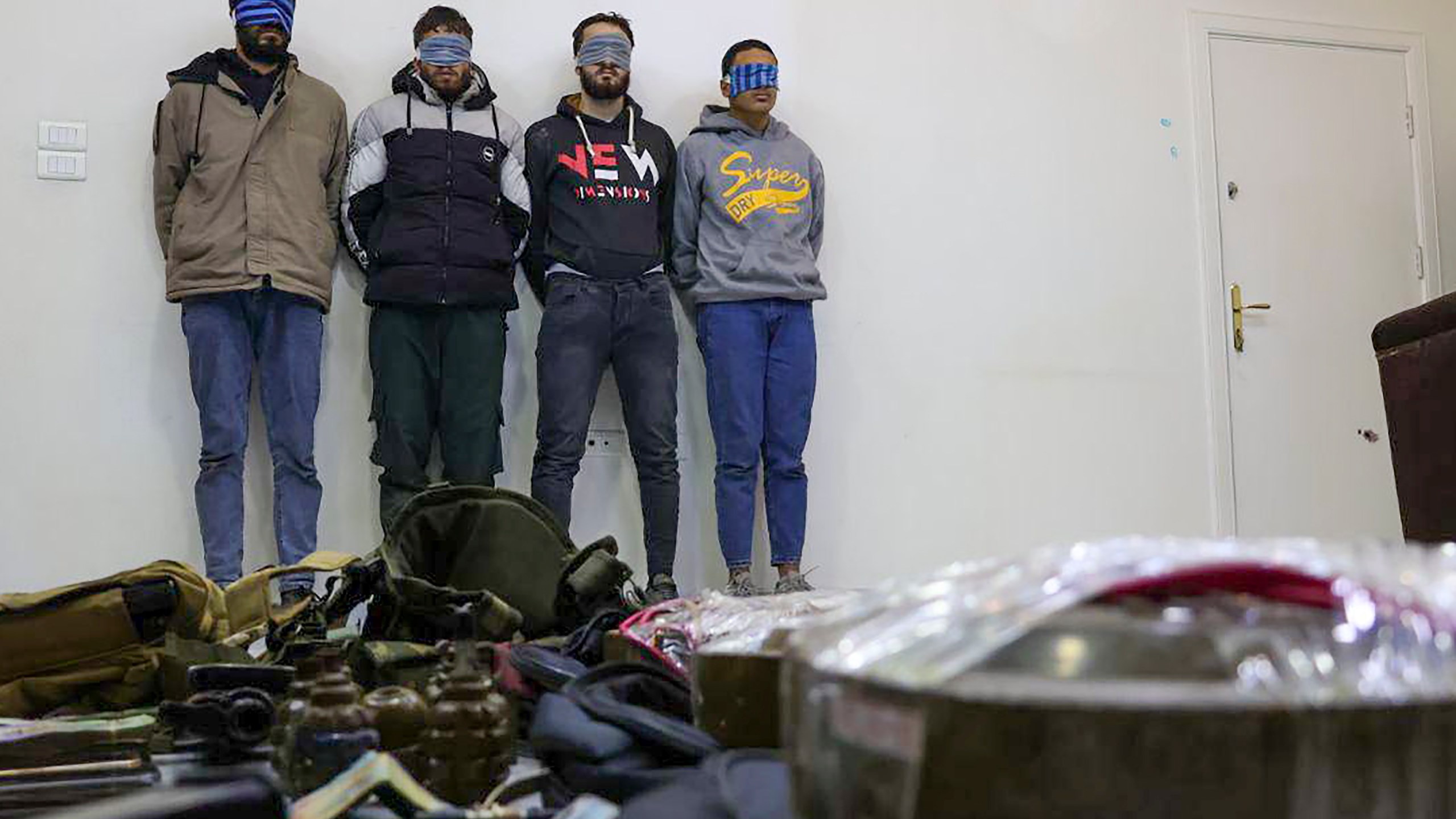 In this photo released by Syrian State TV, four suspects arrested in connection with an alleged plot by ISIS are shown standing against a wall in Damascus, Syria, Saturday, Jan. 11, 2025. Syrian intelligence officials, operating under the country's new de facto government, thwarted an attempt by ISIS to detonate a bomb at the Shiite shrine of Sayyida Zaynab in the Damascus suburb, according to state media reports on Saturday.(Syrian State TV via AP)