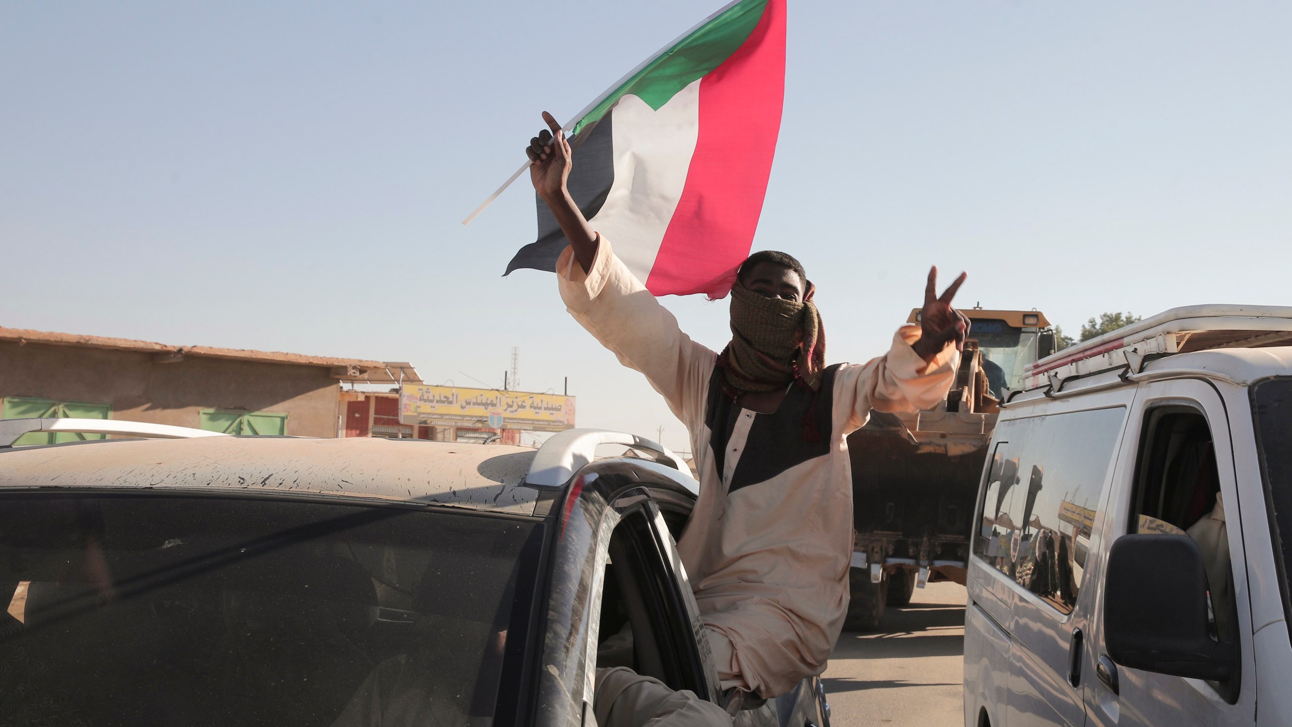 A Sudanese man gestures waving a Sudan flag following the reports that Sudan's army had entered the central city of Wad Madani and pushed out its paramilitary rivals the Rapid Support Forces (RSF), in Merowe, Sudan, Saturday, Jan.11, 2025. (AP Photo/Marwan Ali)