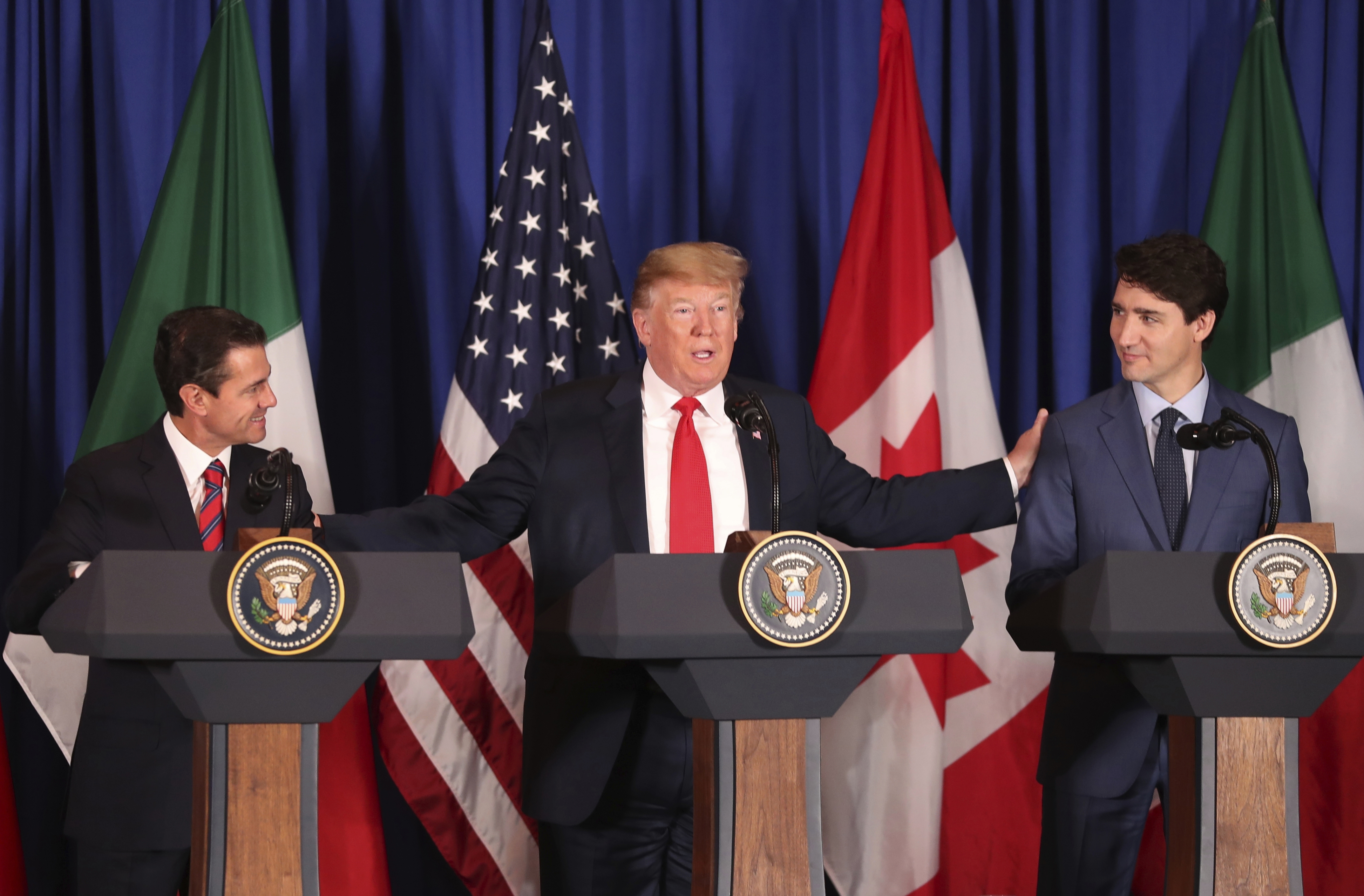 FILE - President Donald Trump, center, reaches out to Mexico's President Enrique Pena Nieto, left, and Canada's Prime Minister Justin Trudeau as they prepare to sign a new United States-Mexico-Canada Agreement that is replacing the NAFTA trade deal during a ceremony at a hotel before the start of the G20 summit in Buenos Aires, Argentina, on Nov. 30, 2018. (AP Photo/Martin Mejia, File)