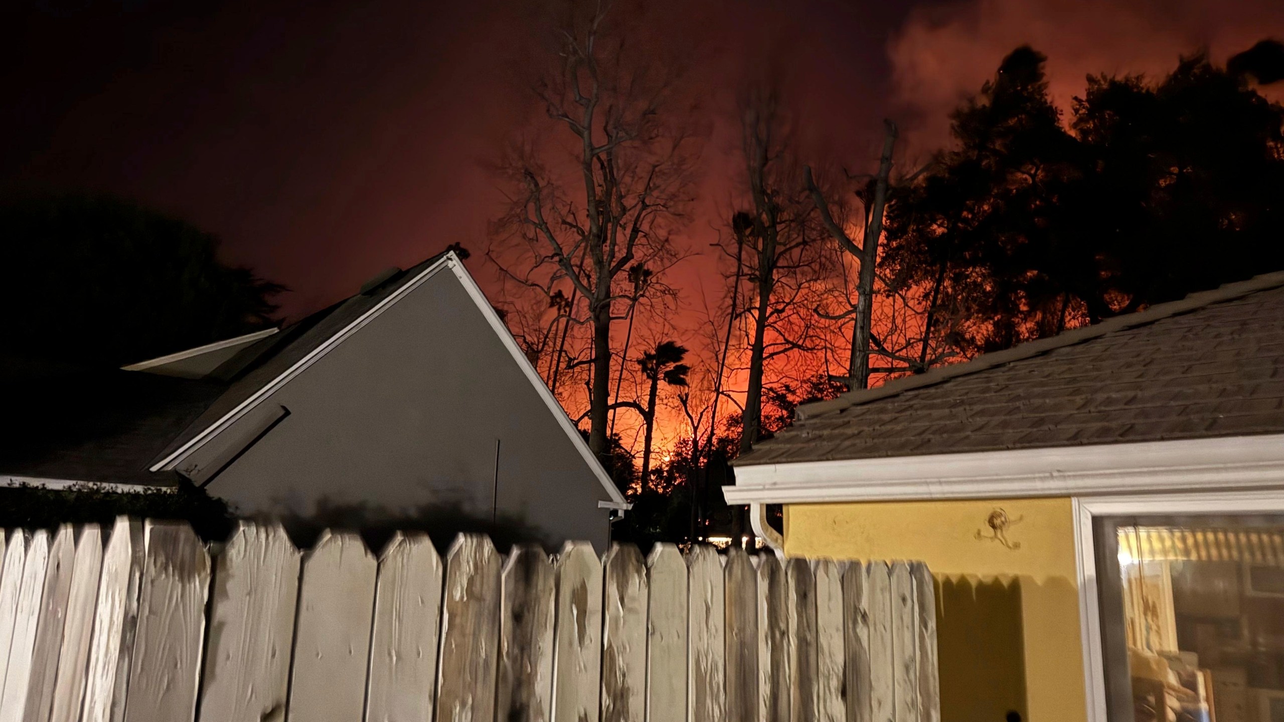 The Eaton wildfire approaches the yellow home of the Prata family in Altadena, California, the night of Tuesday, Jan. 7, 2025. (AP Photo/Vanessa Prata)