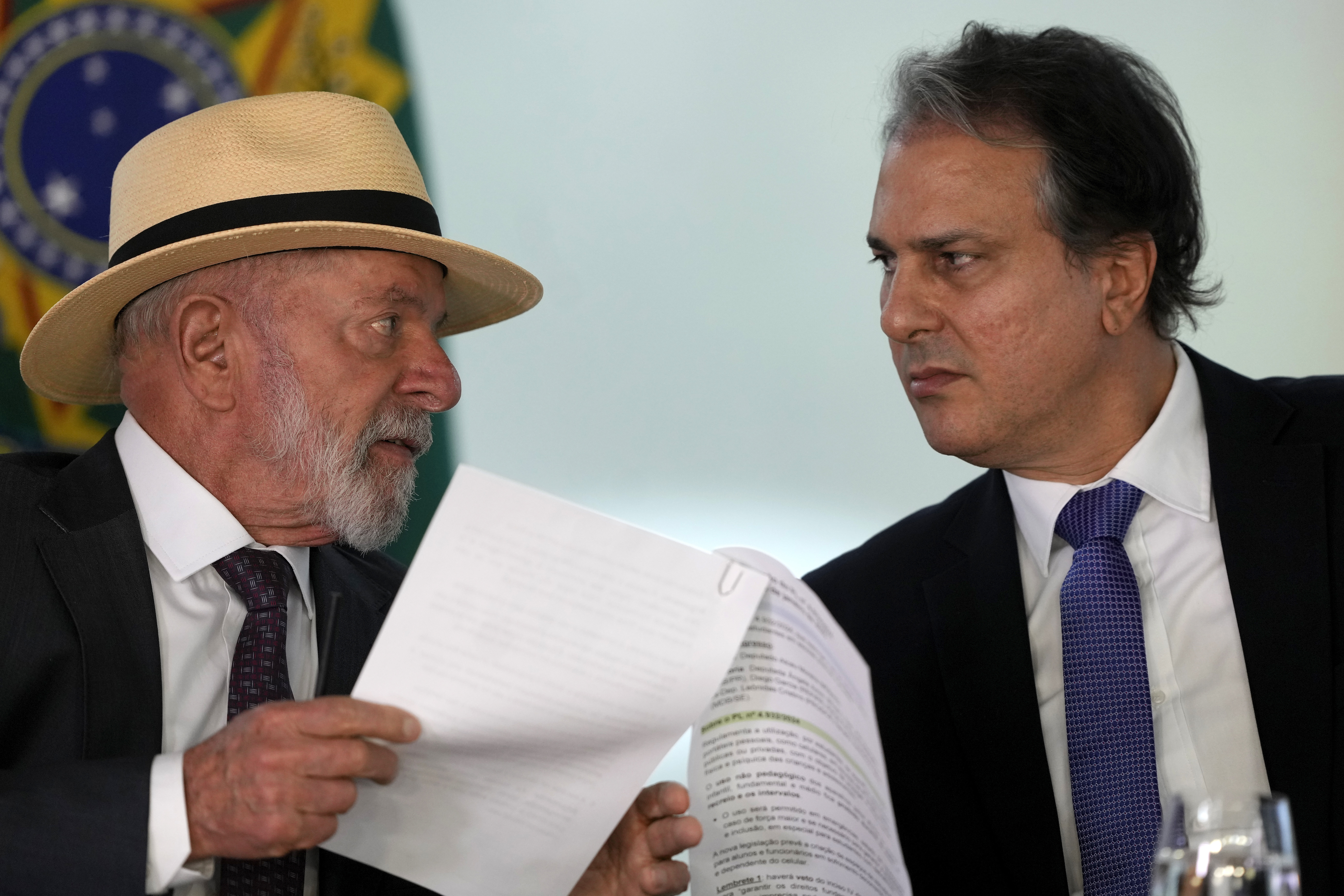 Brazil's President Luiz Inacio Lula da Silva, left, speaks with Education Minister Camilo Santana, about a bill that restricts the use of cell phones in schools nationwide, during a ceremony at the Planalto Palace, in Brasilia, Brazil, Monday, Jan. 13, 2025. (AP Photo/Eraldo Peres)