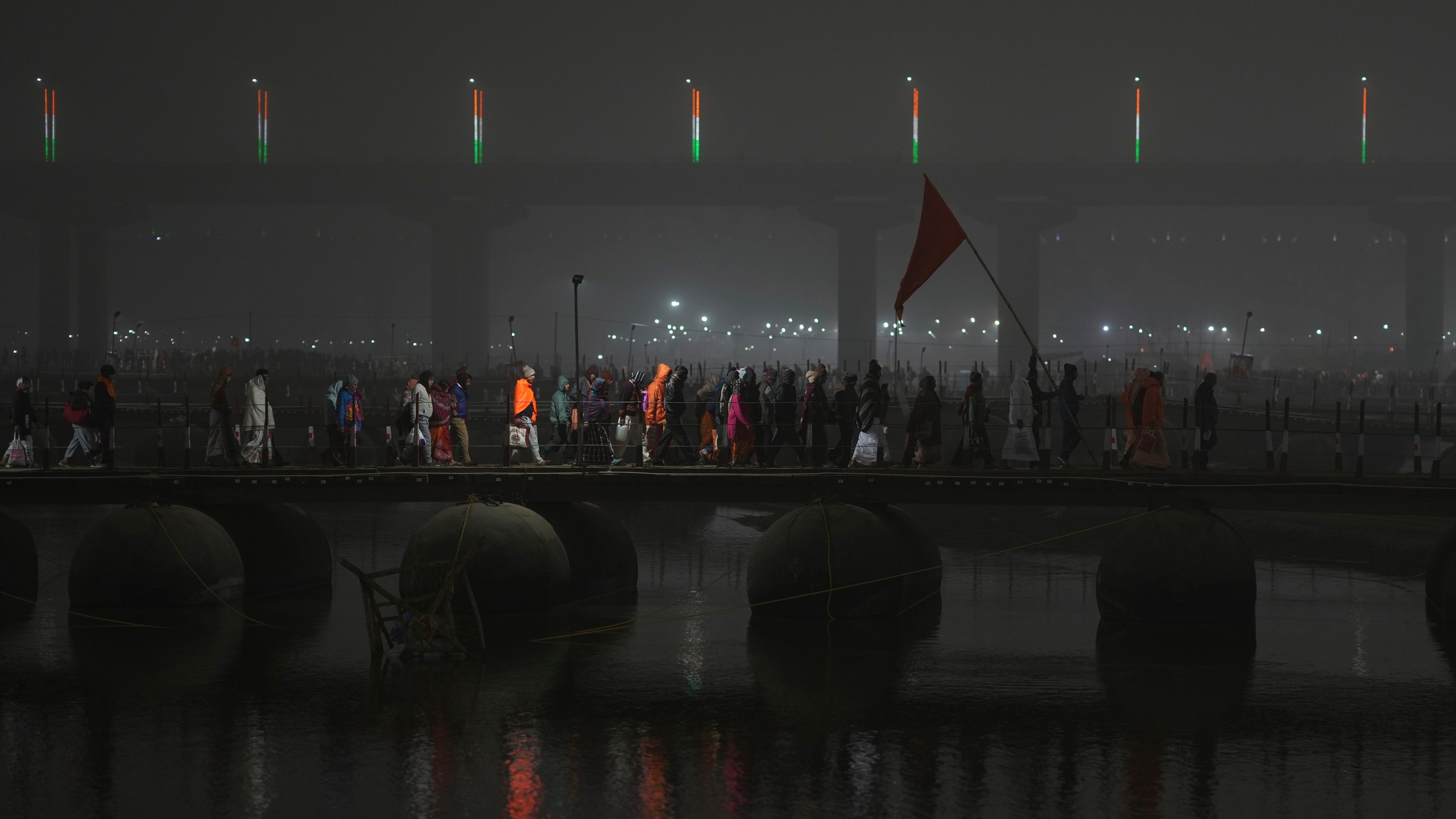 Hindu devotees cross a pontoon bridge after taking a dip at Sangam, the confluence of the Rivers Ganges, Yamuna and mythical Saraswati on one of the most auspicious day Makar Sankranti, for the Mahakumbh festival, which is one of the world's largest religious gatherings, celebrated every 12 years in Prayagraj, in the northern Indian state of Uttar Pradesh, India, Tuesday, Jan. 14, 2025. (AP Photo/Rajesh Kumar Singh)