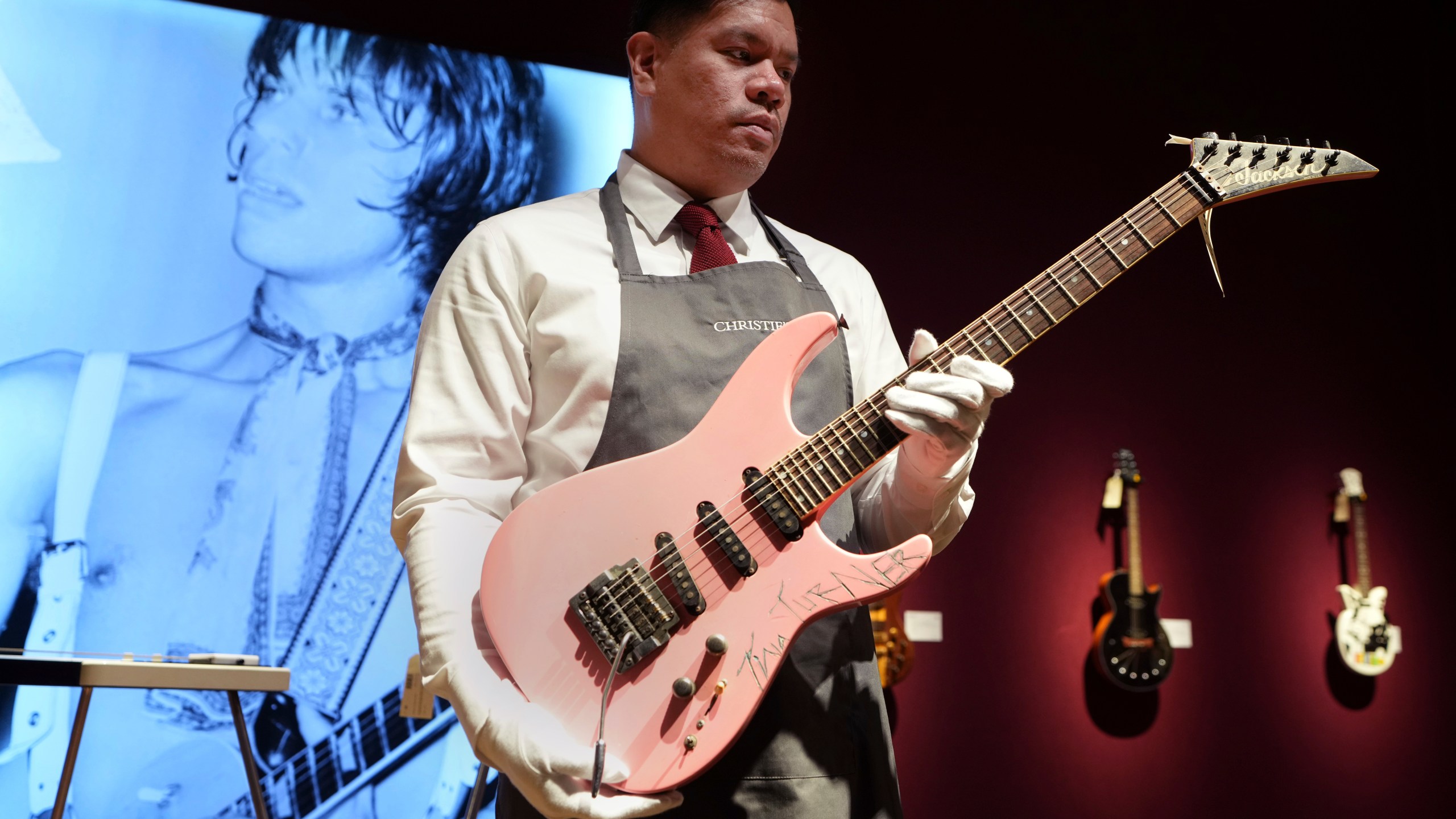 An art handler displays a Jackson, Glendora, California, 1983, a solid-body electric guitar, soloist, signed by Tina Turner, ahead of the pre-sale exhibition of Jeff Beck The Guitar Collection at Christie's auction rooms in London, Tuesday, Jan. 14, 2025. (AP Photo/Kirsty Wigglesworth)