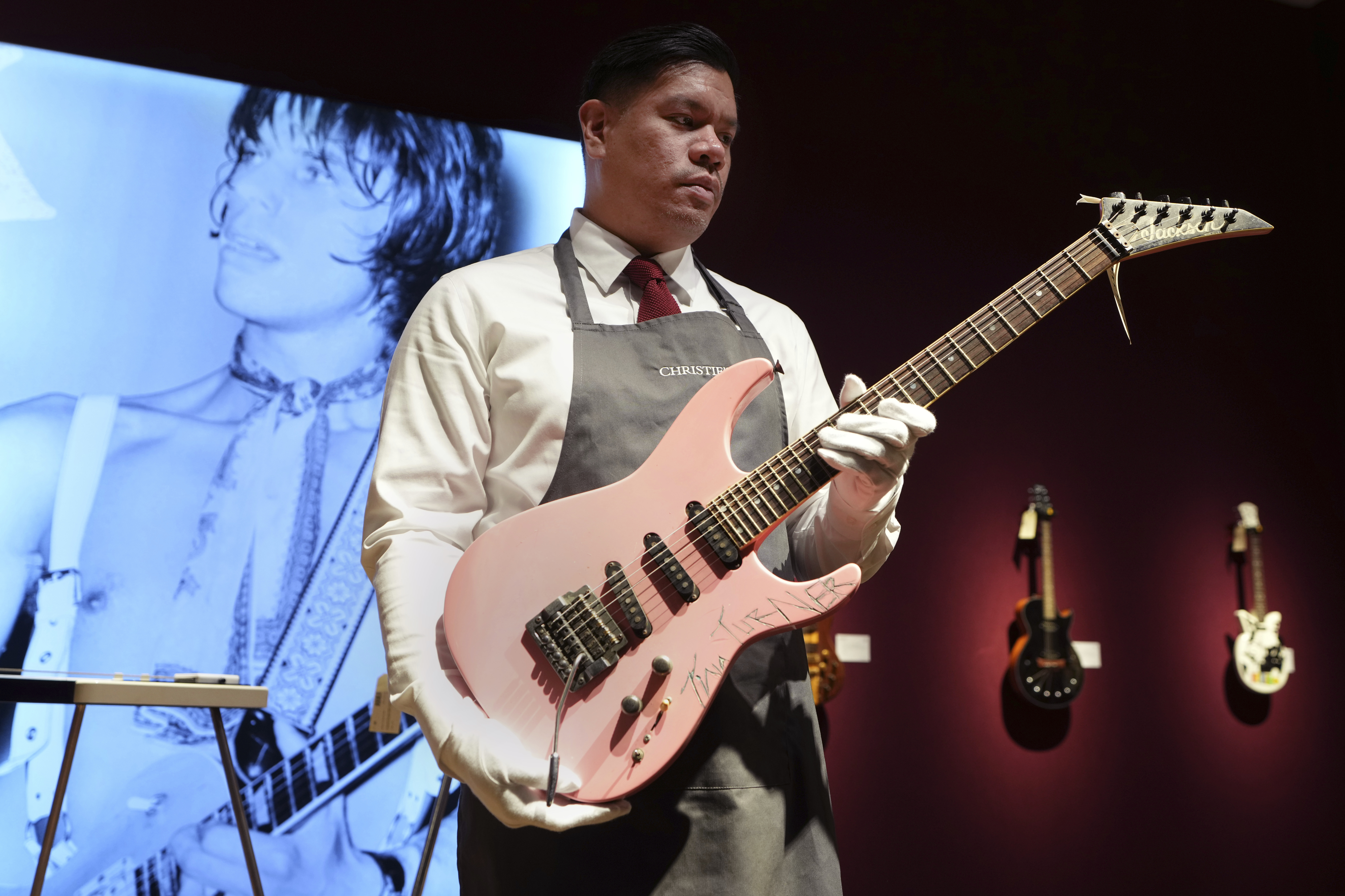 An art handler displays a Jackson, Glendora, California, 1983, a solid-body electric guitar, soloist, signed by Tina Turner, ahead of the pre-sale exhibition of Jeff Beck The Guitar Collection at Christie's auction rooms in London, Tuesday, Jan. 14, 2025. (AP Photo/Kirsty Wigglesworth)