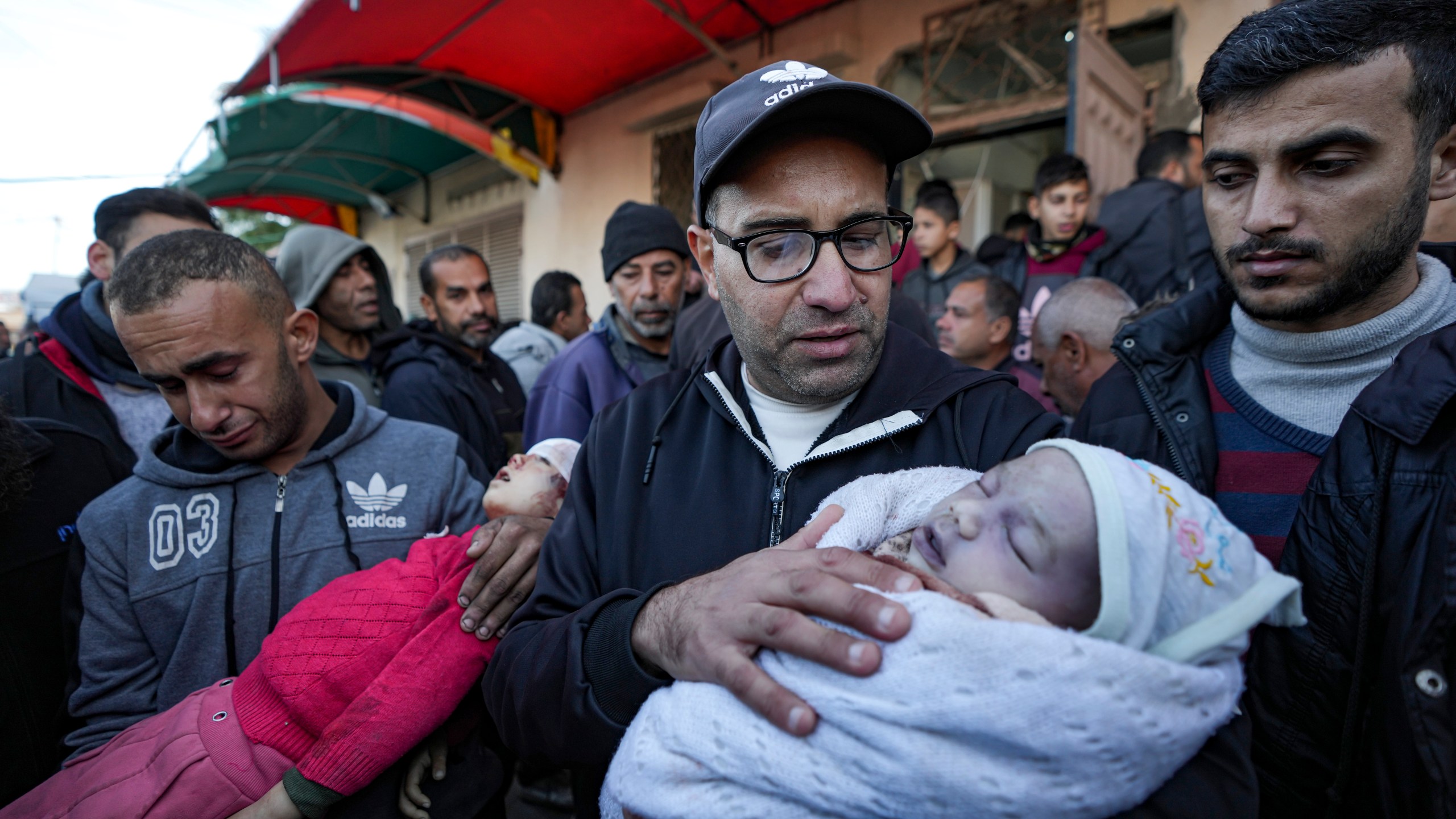 EDS NOTE: GRAPHIC CONTENT - Relatives react as they carry the bodies of children who were killed by an Israeli airstrike on the Gaza Strip at the Al-Aqsa Hospital in Deir al-Balah, Tuesday, Jan. 14, 2025. (AP Photo/Abdel Kareem Hana)