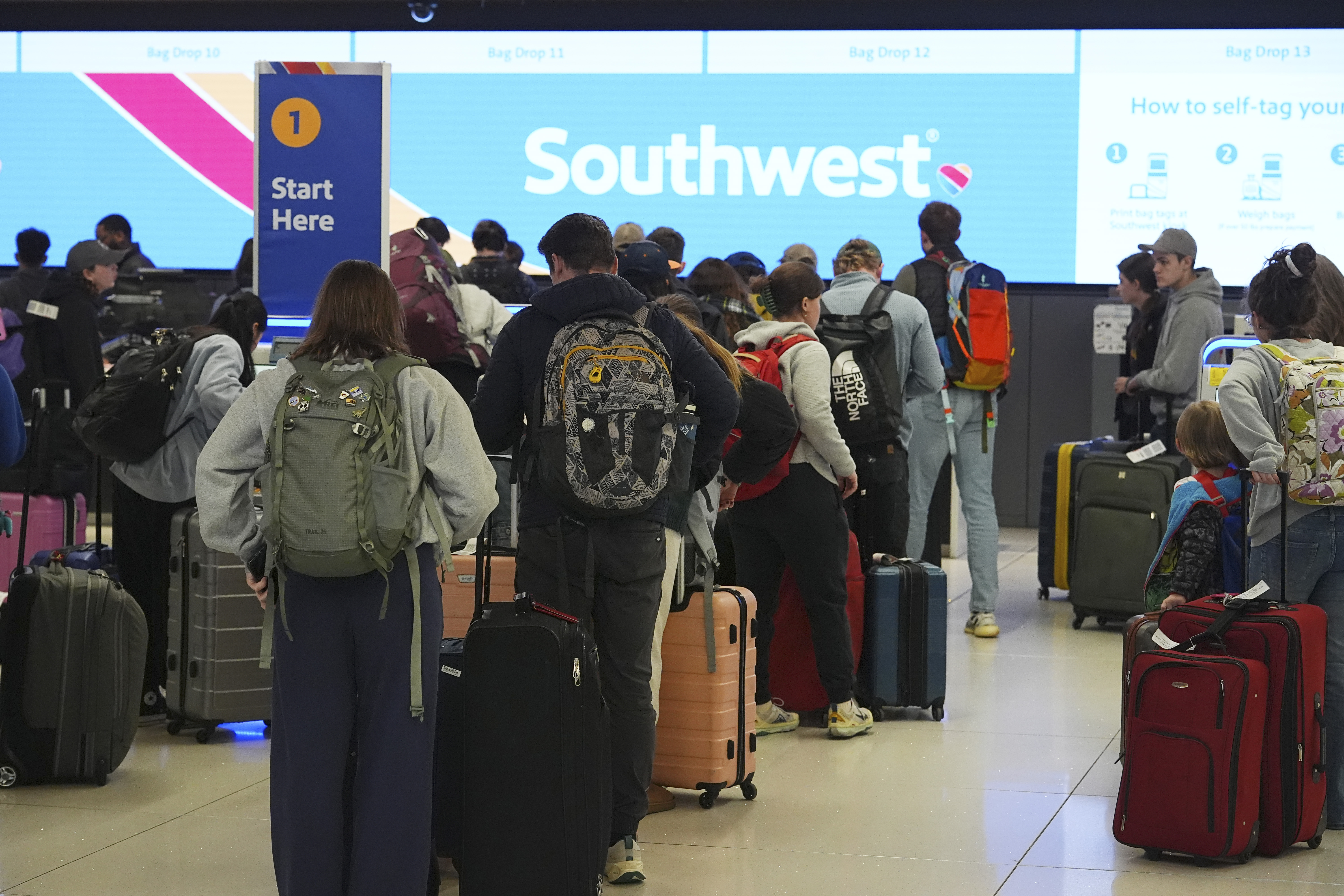 Travelers wait at the check-in counter for Southwest Airlines in Denver International Airport Thursday, Dec. 19, 2024, in Denver. (AP Photo/David Zalubowski)