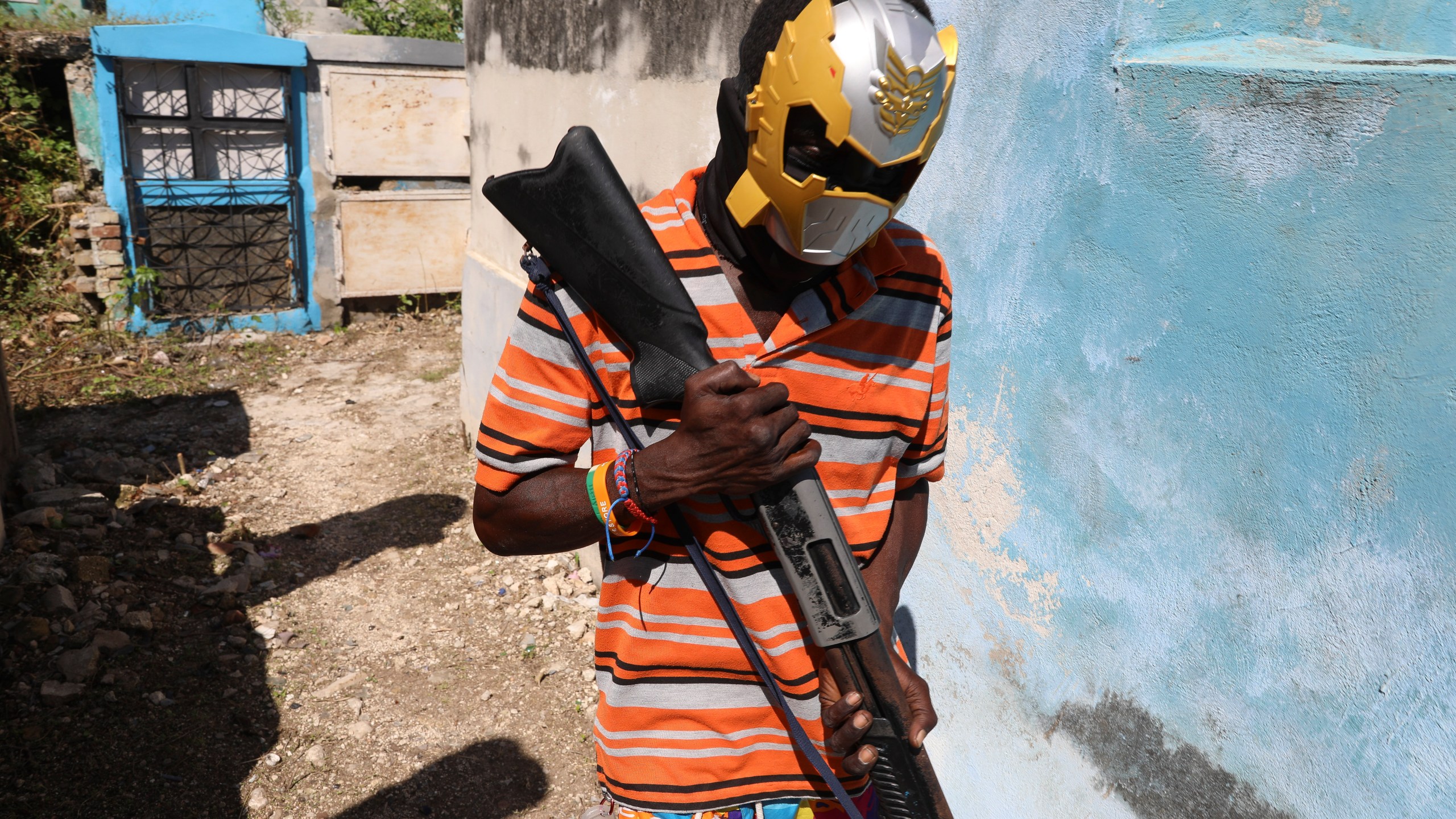 A masked, armed gang member poses for a photo at the National Cemetery during the Fete Gede festival celebrating Day of the Dead to honor the Haitian Vodou spirits Baron Samedi and Gede in Port-au-Prince, Haiti, Nov. 1, 2024. (AP Photo/Odelyn Joseph)