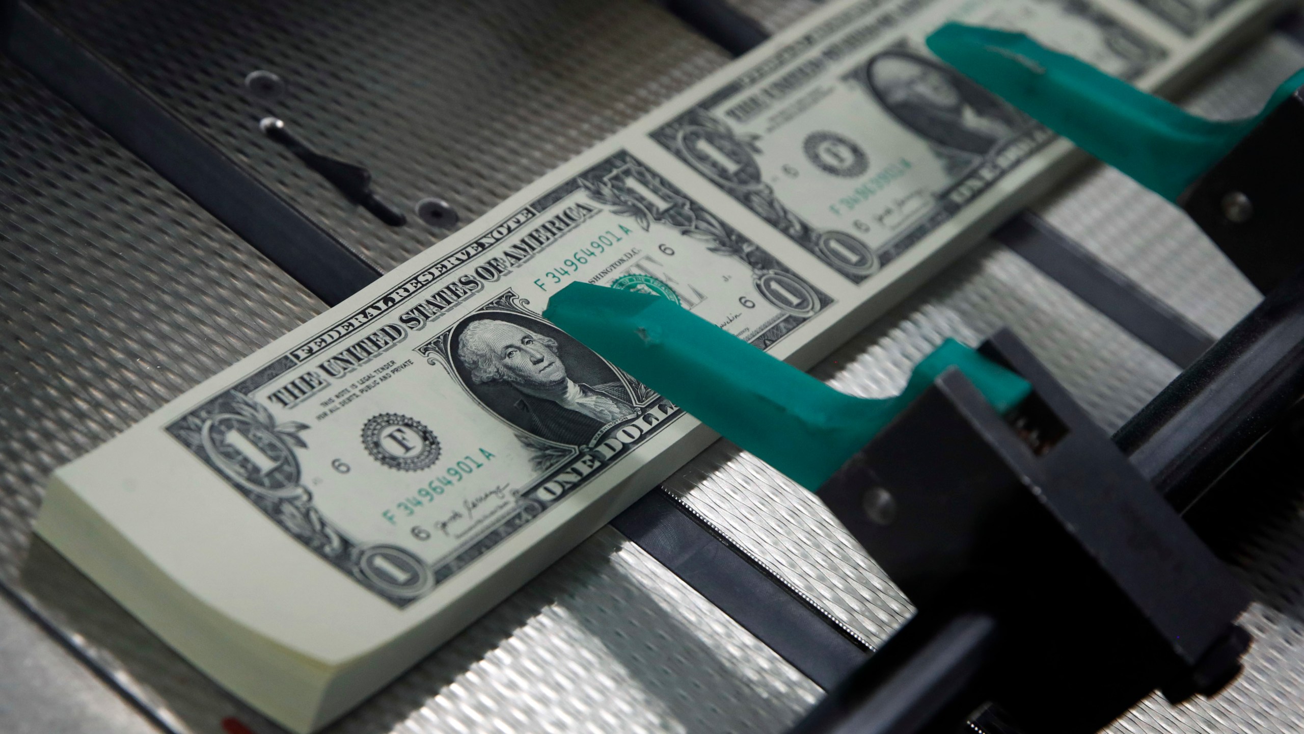 FILE- In this Nov. 15, 2017, file photo, new $1 bills are cut and stacked at the Bureau of Engraving and Printing in Washington. (AP Photo/Jacquelyn Martin, File)