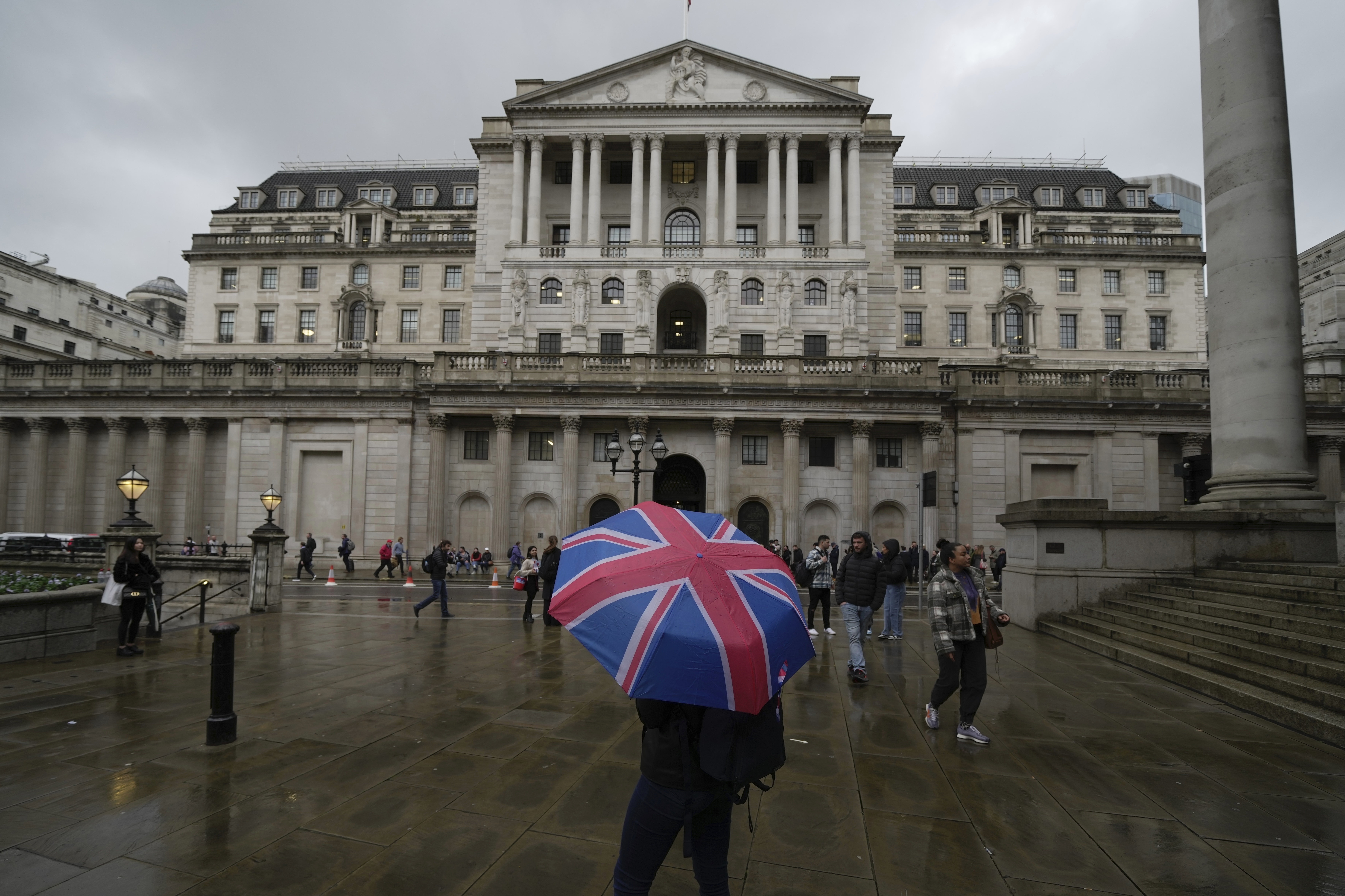 FILE -A woman with an umbrella stands in front of the Bank of England, at the financial district in London, , Nov. 3, 2022. (AP Photo/Kin Cheung, File)