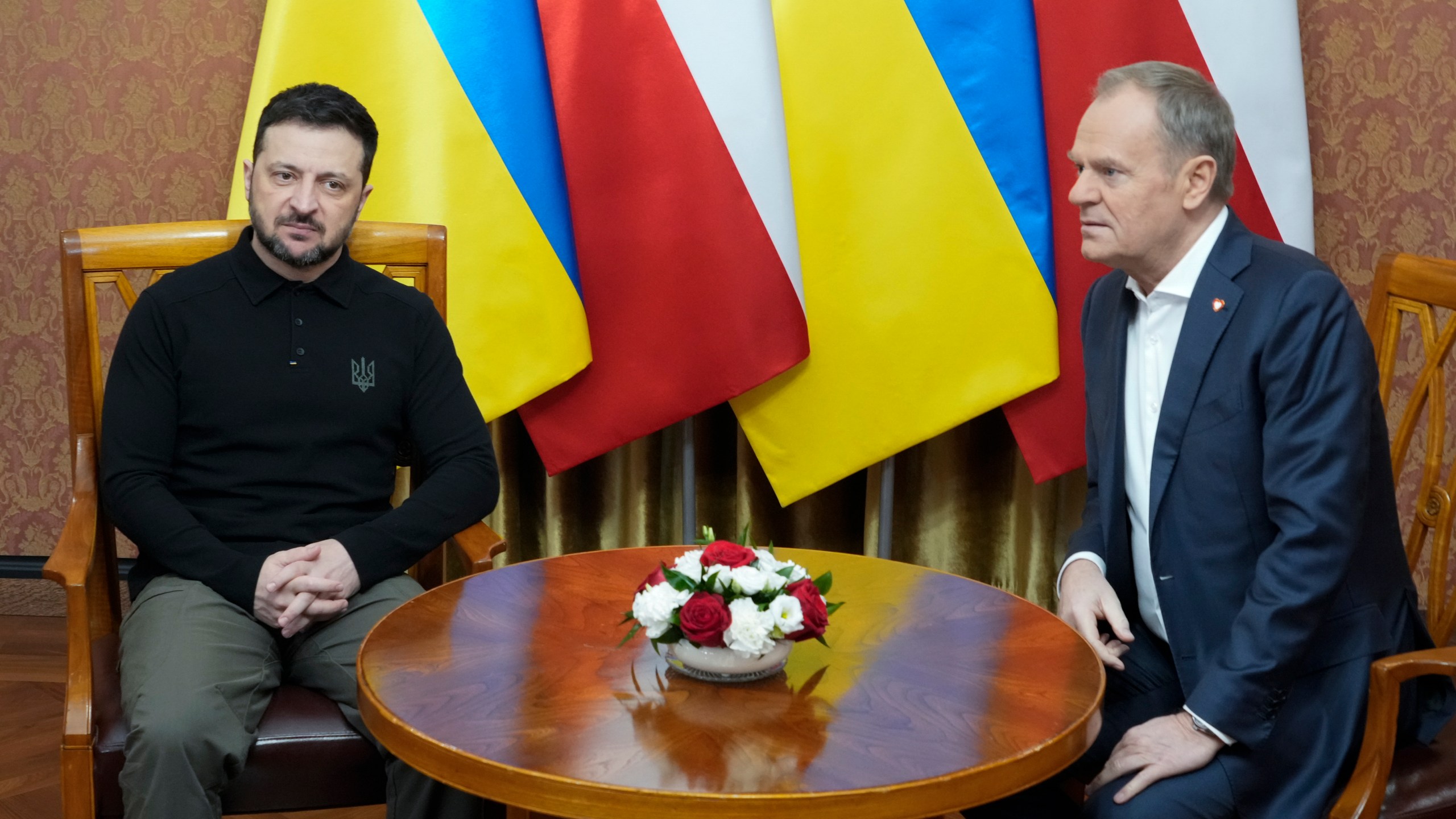 Polish Prime Minister Donald Tusk, right, speaks with Ukrainian President Volodymyr Zelenskyy after the two countries reached an agreement on a longstanding source of tensions between them: the exhumation of Polish victims of World War II-era massacres by Ukrainian nationalists, in Warsaw, Poland, on Wednesday, Jan. 15, 2025. (AP Photo/Czarek Sokolowski)