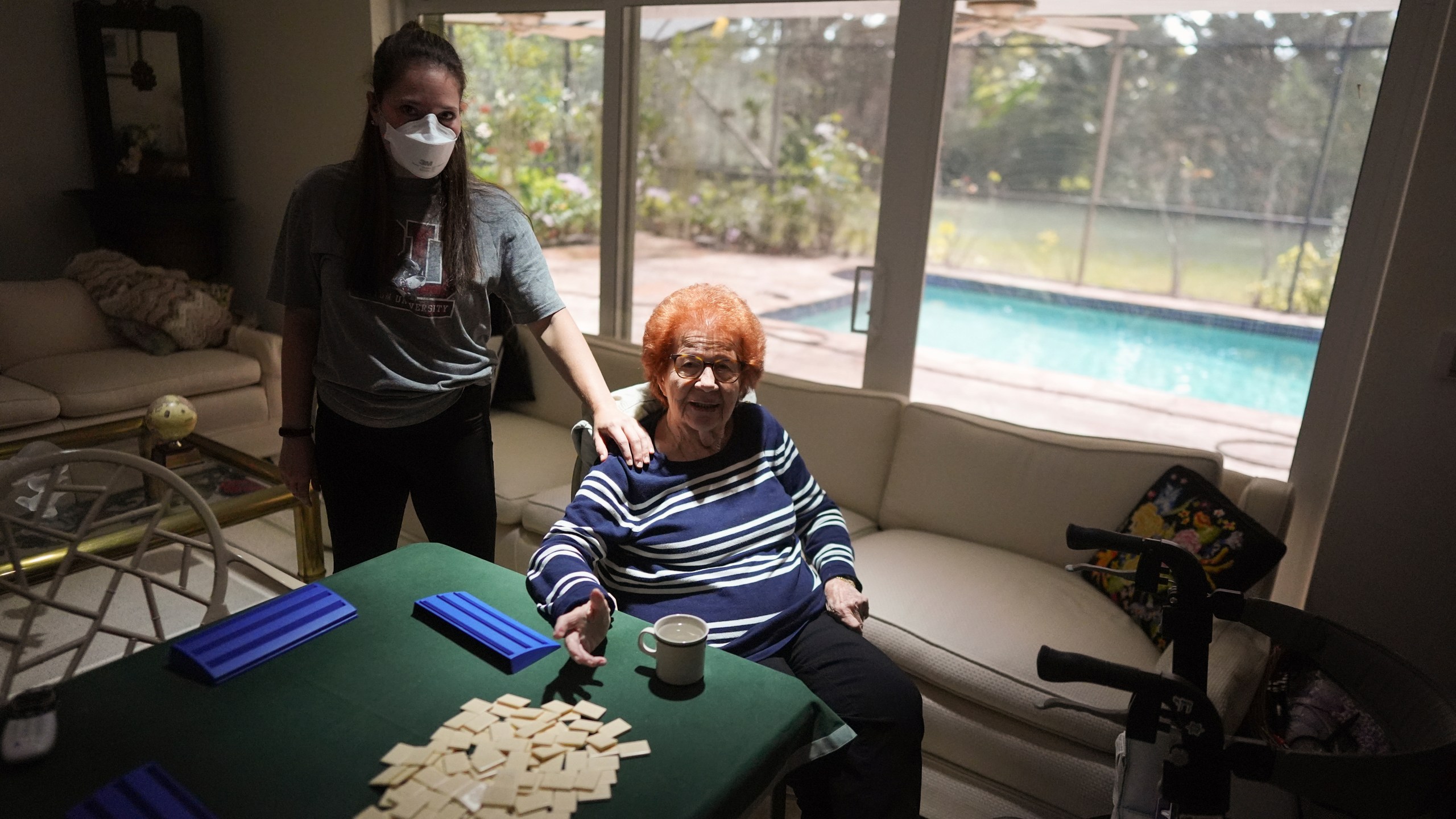 Kira Levin, 29, left, stands with her 98-year-old grandmother Jeanette Levin, in their living room in Pinecrest, Fla., Monday, Dec. 16, 2024. Kira, who moved back in with her parents when COVID hit as she was finishing her masters degree, has become a primary caregiver to her grandmother while also working from home. (AP Photo/Rebecca Blackwell)