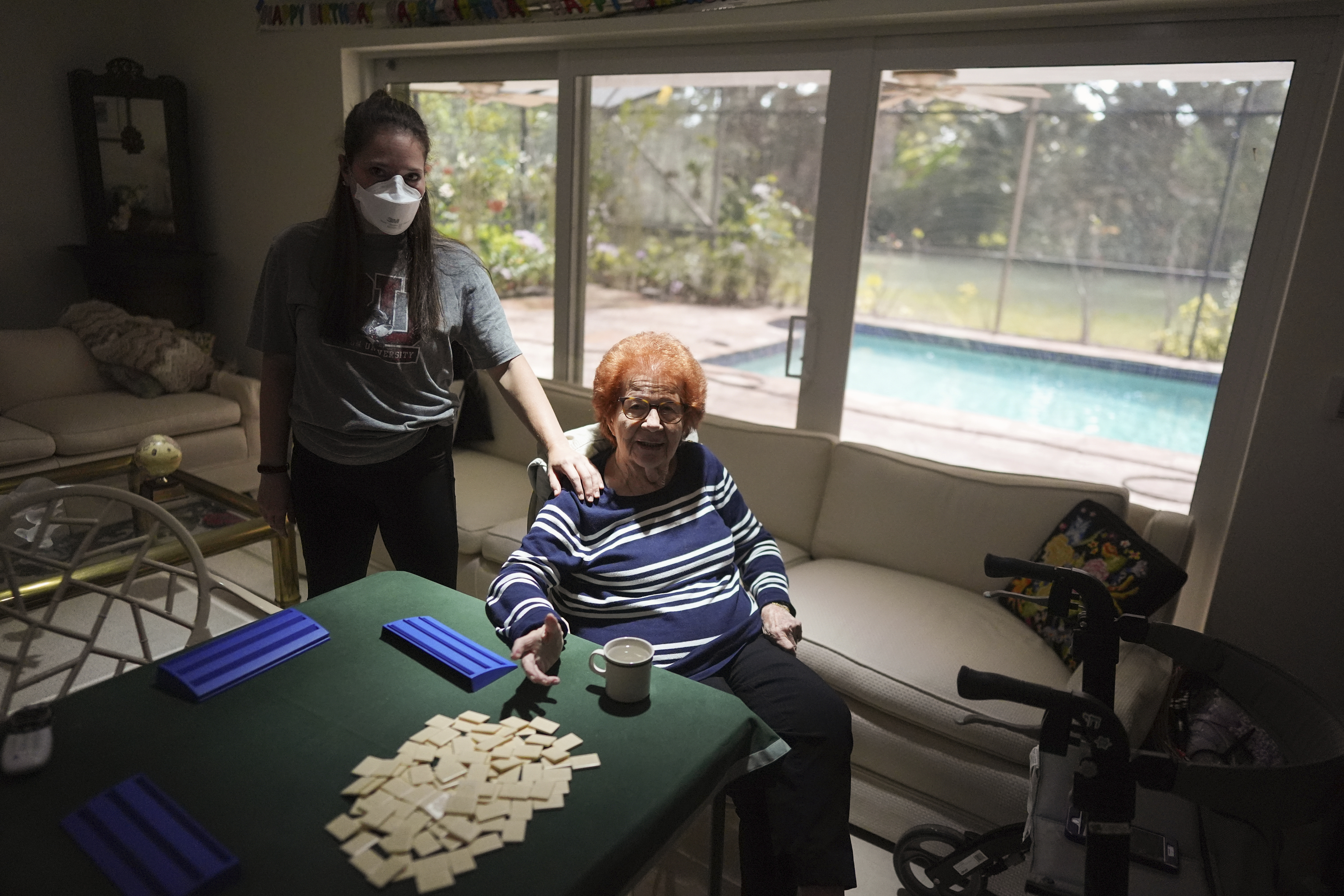 Kira Levin, 29, left, stands with her 98-year-old grandmother Jeanette Levin, in their living room in Pinecrest, Fla., Monday, Dec. 16, 2024. Kira, who moved back in with her parents when COVID hit as she was finishing her masters degree, has become a primary caregiver to her grandmother while also working from home. (AP Photo/Rebecca Blackwell)