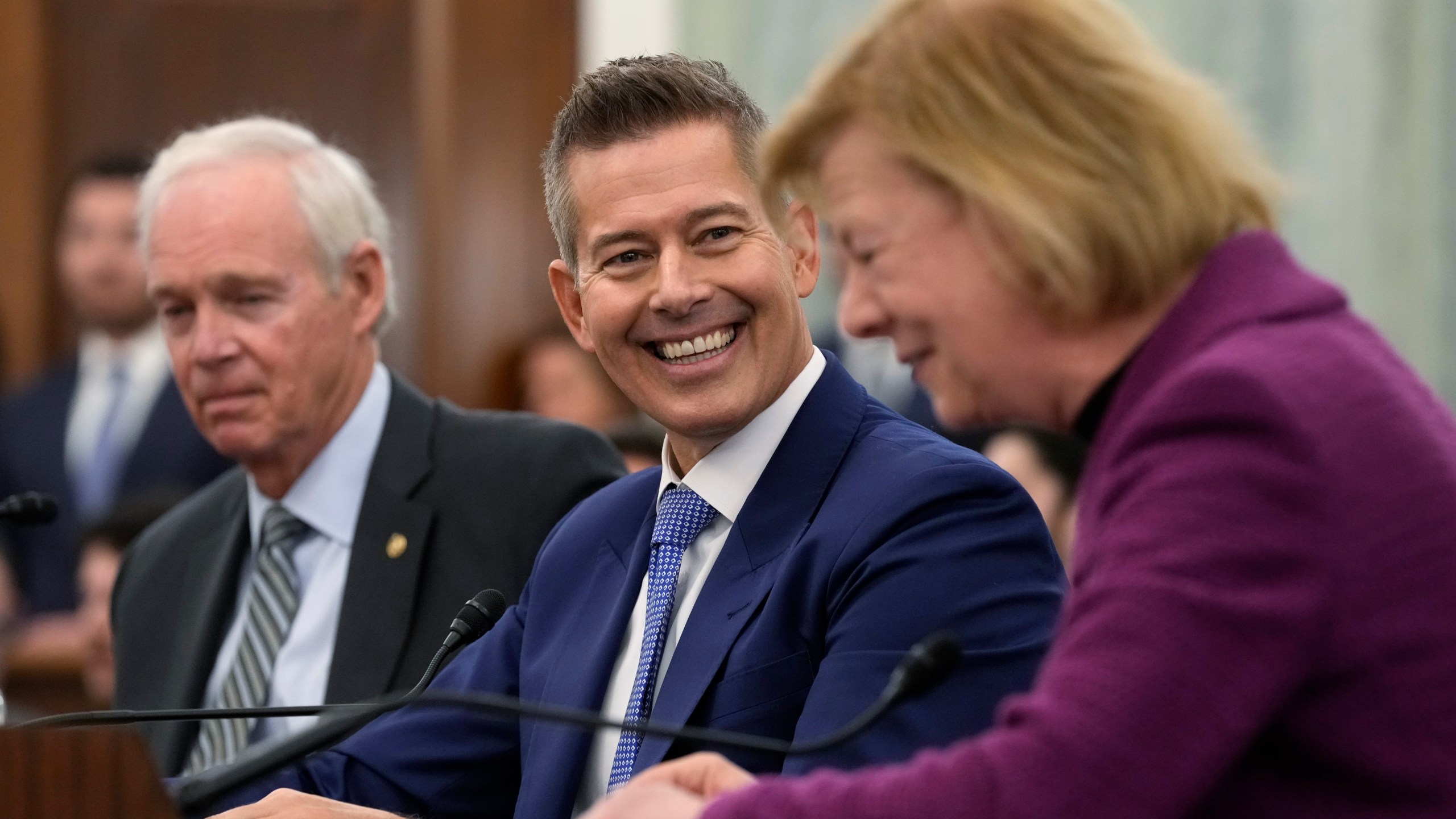 Former Wisconsin Rep. Sean Duffy, R-Wis., center, smiles as Sen. Tammy Baldwin, D-Wis., right, introduces him before he testifies before the Senate Commerce, Science, and Transportation Committee on Capitol Hill in Washington, Wednesday, Jan. 15, 2025, to be Transportation Secretary. Sen. Ron Johnson, R-Wis., left, also introduced Duffy. (AP Photo/Susan Walsh)