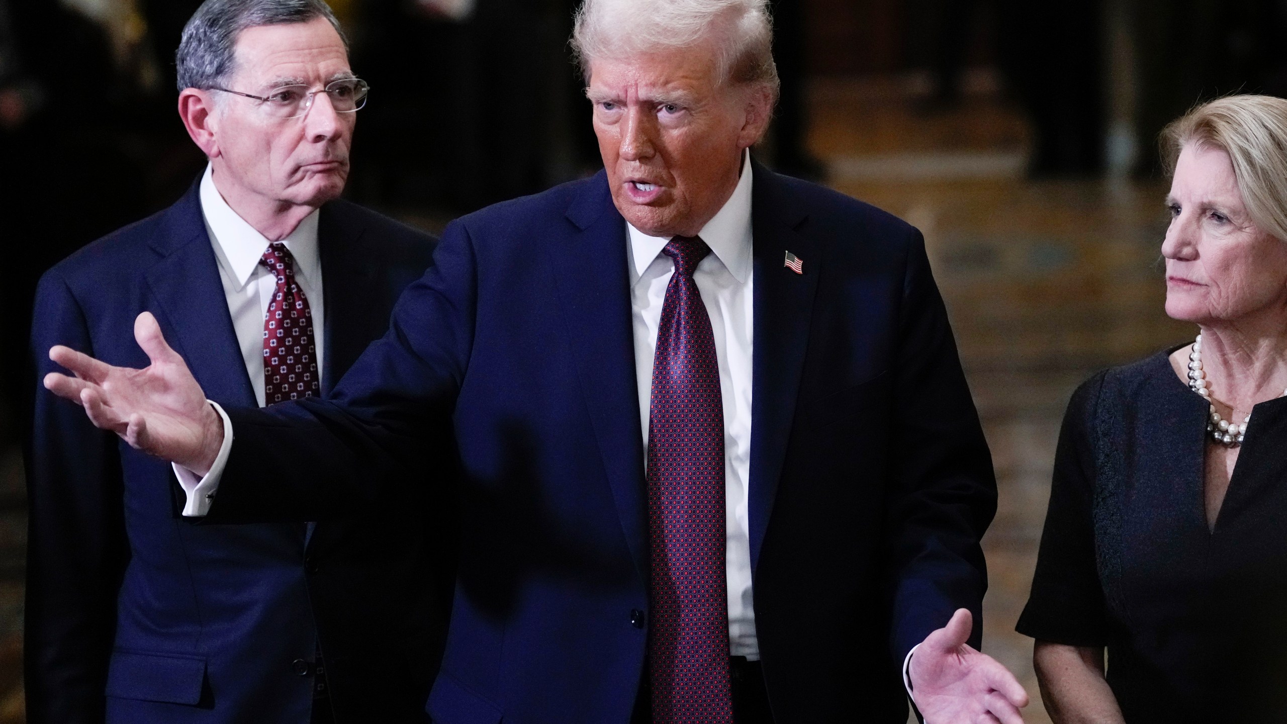 FILE - President-elect Donald Trump talks to reporters after a meeting with Republican leadership at the Capitol, Jan. 8, 2025, in Washington. At left is Sen. John Barrasso, R-Wyo., and at right is Sen. Shelley Moore Capito, R-W.Va. (AP Photo/Steve Helber, File)