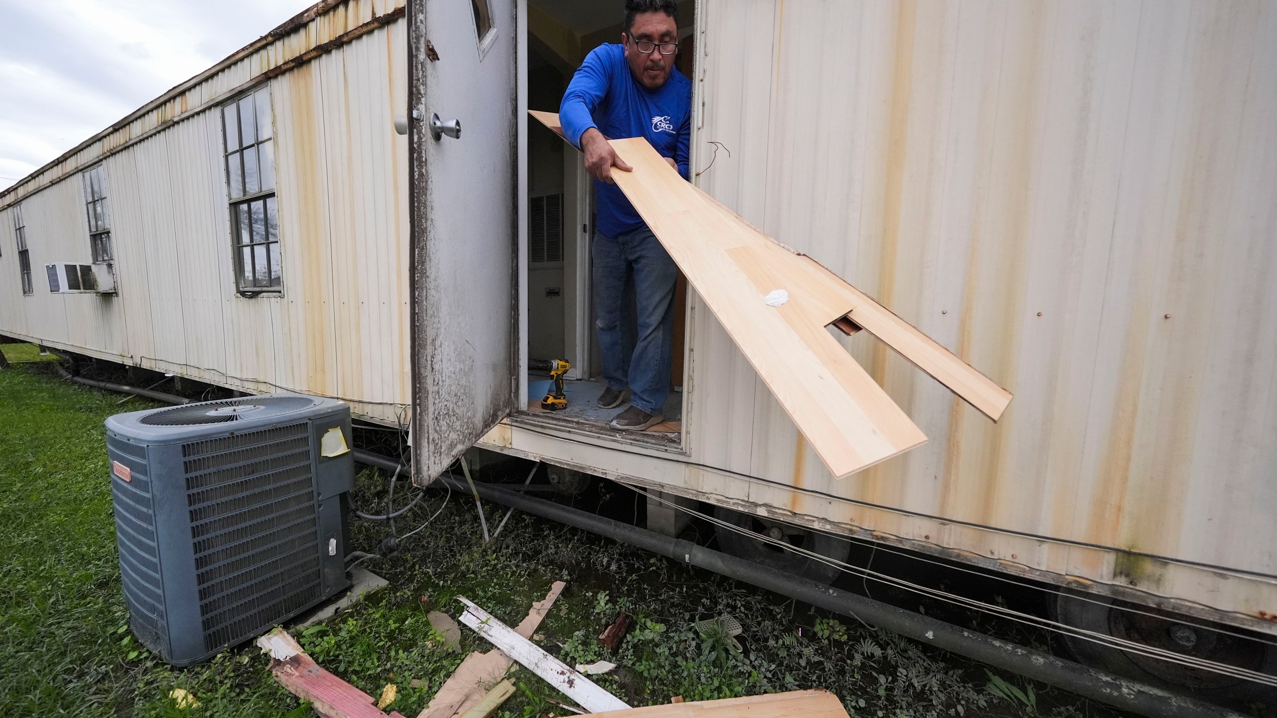 Mario Mendoza works on repairing a mobile home in Belle Chasse, La., Wednesday, Jan. 15, 2025, that was damaged from Hurricane Ida in 2021. (AP Photo/Gerald Herbert)