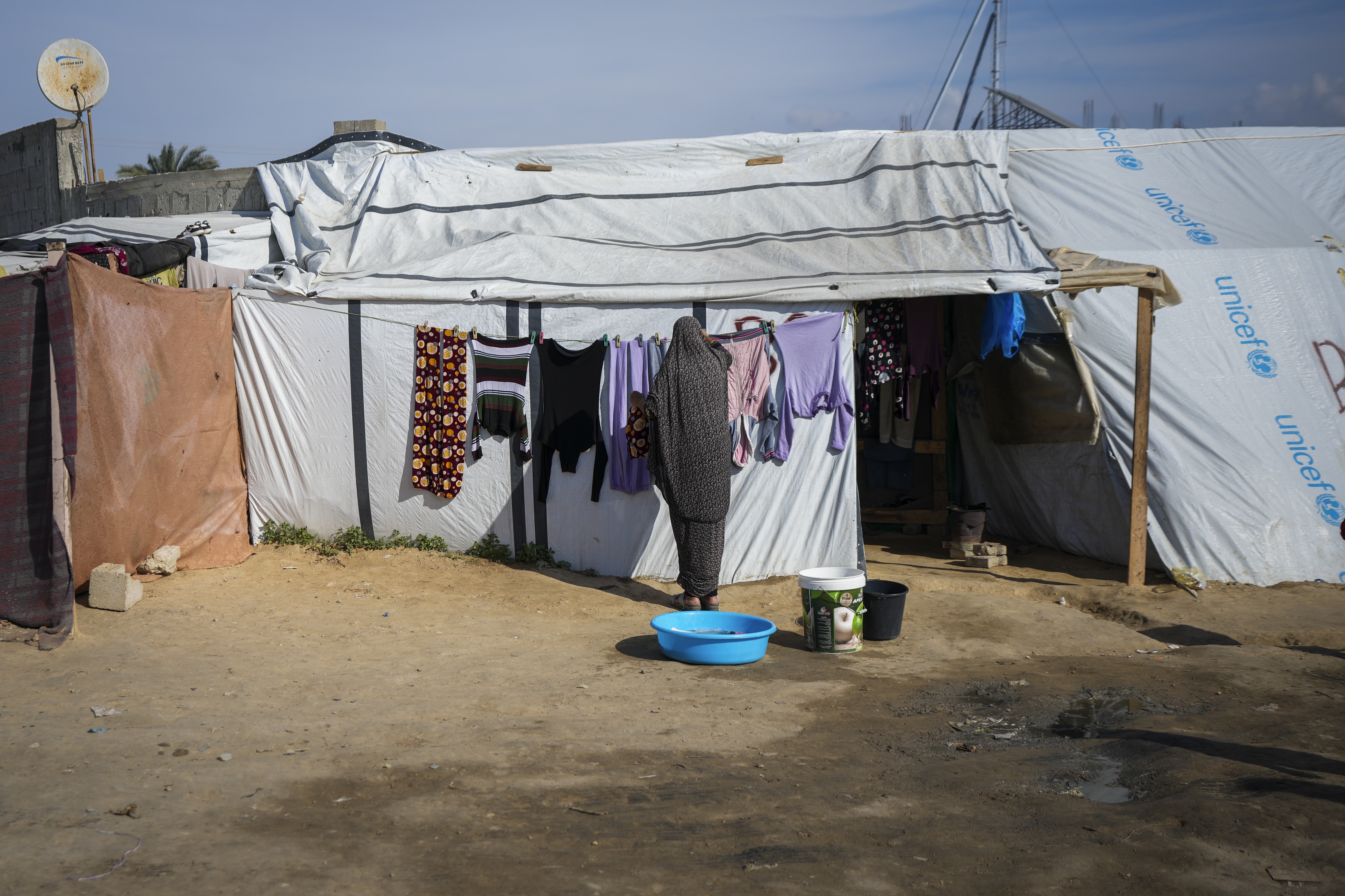 A woman hangs her laundry outside a tent at a camp for displaced Palestinians in Deir al-Balah, central Gaza Strip, Friday Jan. 17, 2025. (AP Photo/Abdel Kareem Hana)