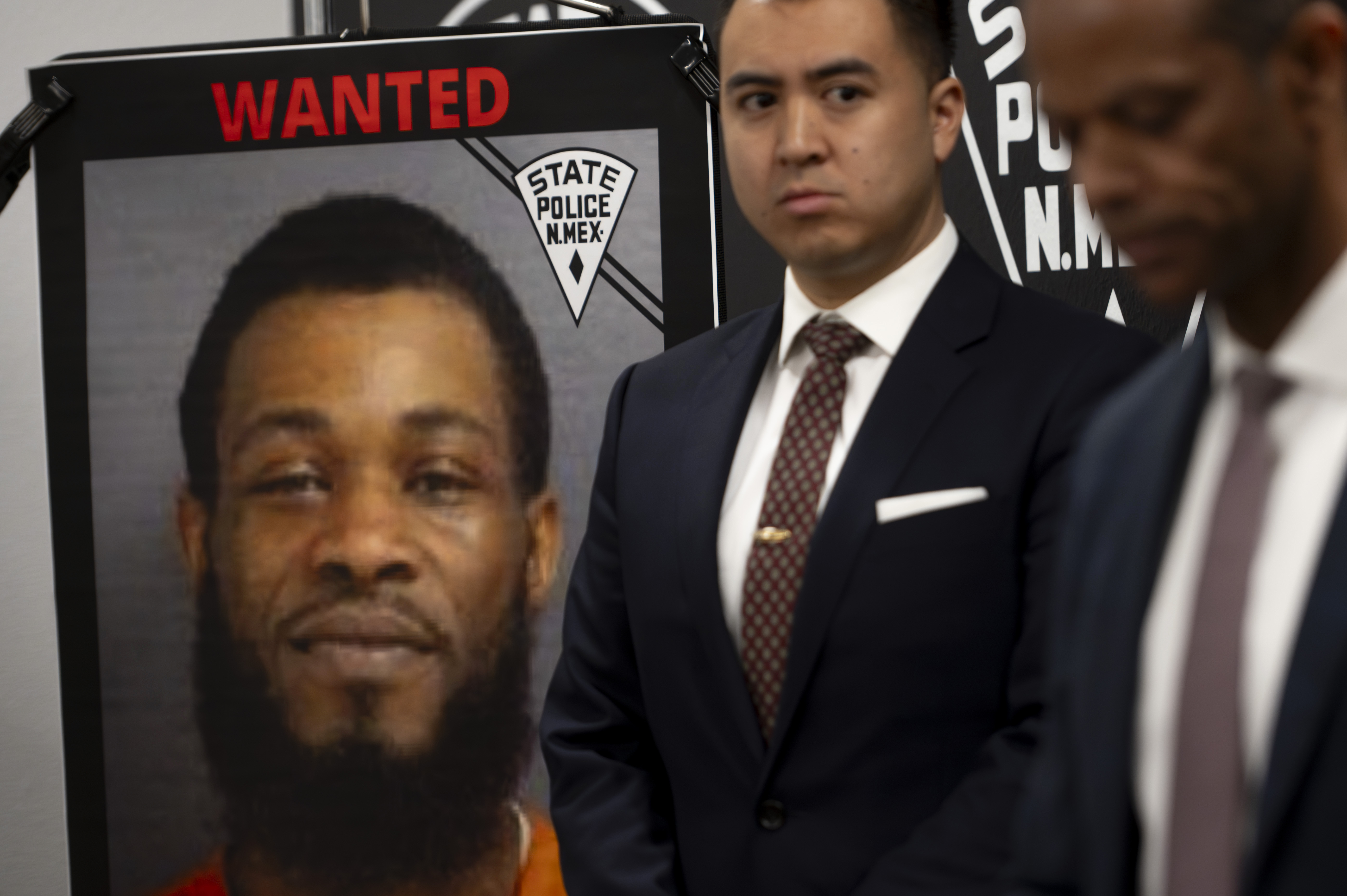 FILE - A wanted poster of Jaremy Smith is displayed beside U.S. Attorney for New Mexico Alexander Uballez, second right, on March 16, 2024, as Public Safety Secretary Jason Bowie gives a briefing following the death of New Mexico State Police officer Justin Hare, in Albuquerque, New Mexico. (Jon Austria/The Albuquerque Journal via AP File)