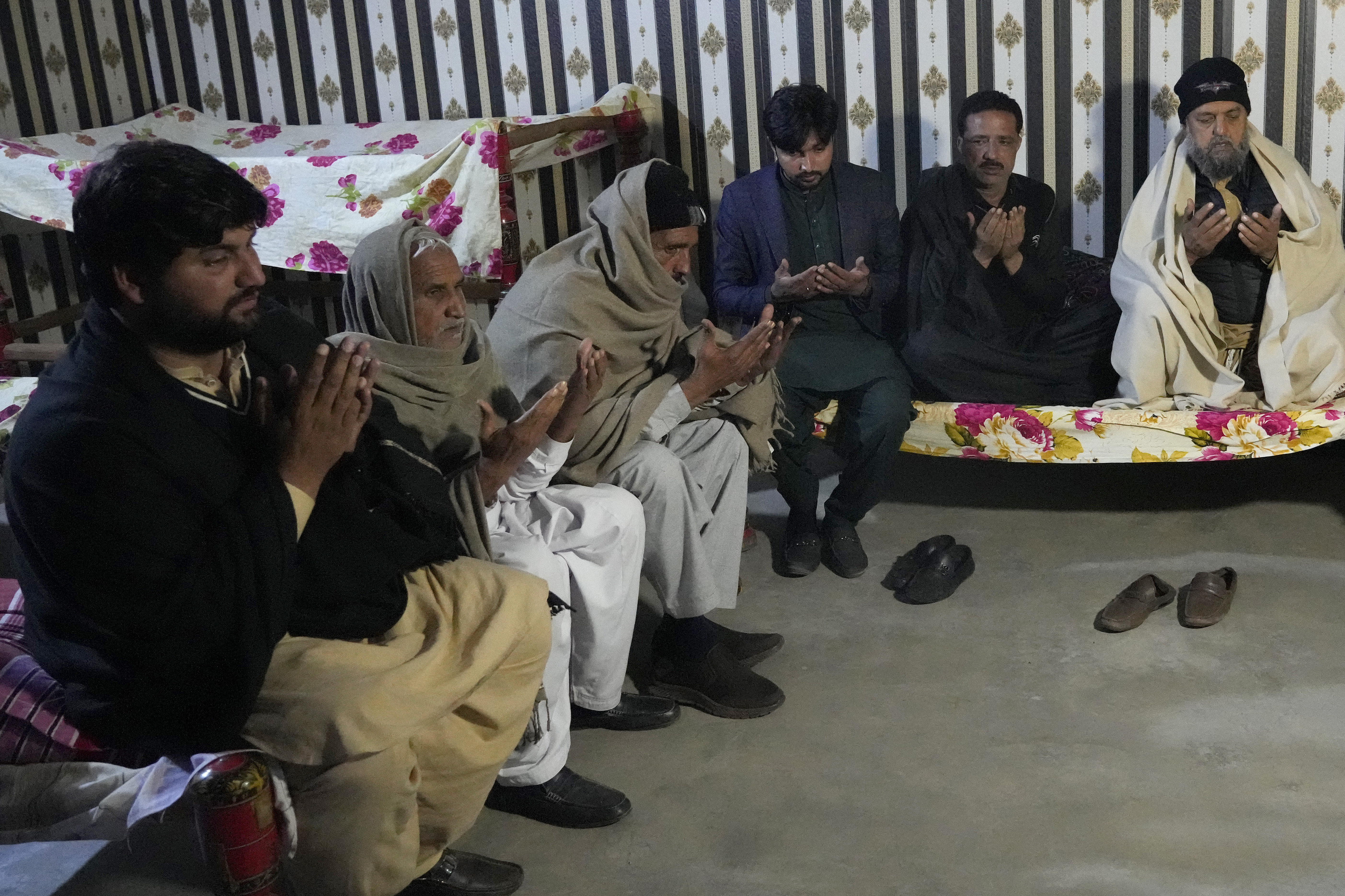 Ahsan Shahzad, father of Suffian Ali, one of the victims of a migrant boat that capsized in West Africa's Atlantic coastline, is consoled by relatives at his home in the village of Dhola, Lalamusa district, Pakistan, Friday, Jan. 17, 2024. (AP Photo/K.M. Chaudary)