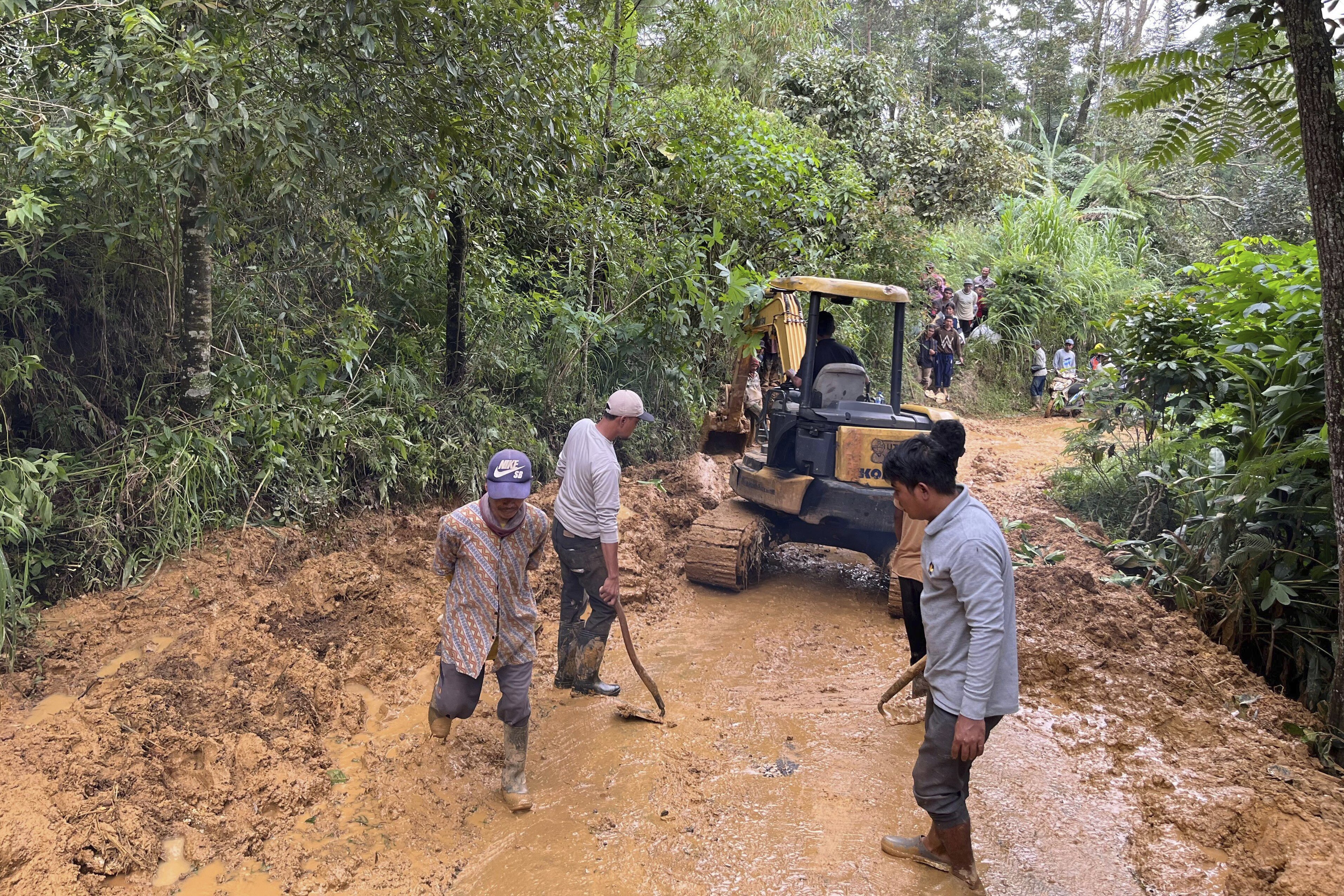 Workers clear a road cut off by a landslide following a flash flood in Pekalongan, Central Java, Indonesia, Wednesday, Jan. 22, 2025. (AP Photo/Janaki DM)