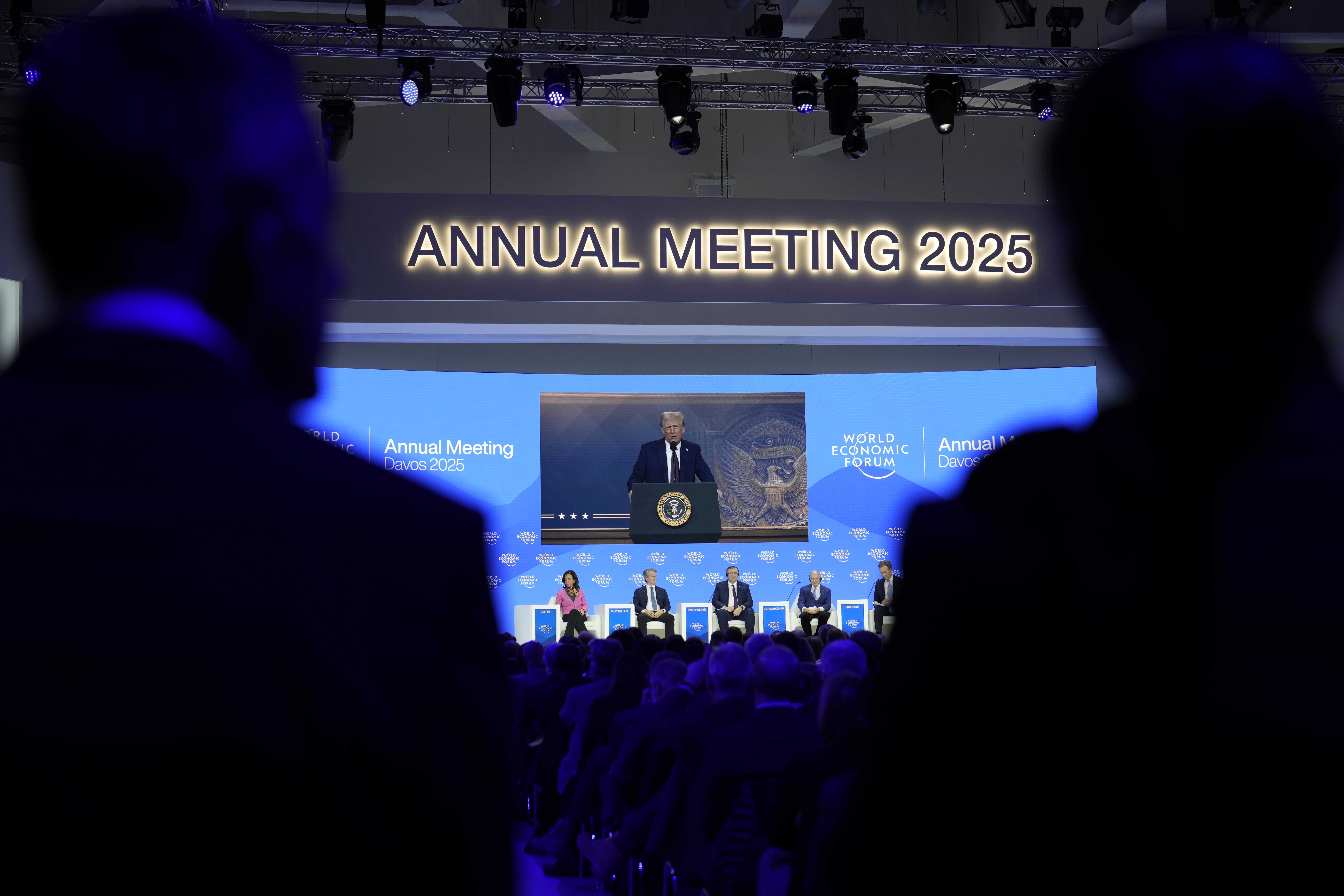 People follow a virtual speech of U.S. president Donald Trump at the Annual Meeting of World Economic Forum in Davos, Switzerland, Thursday, Jan. 23, 2025. (AP Photo/Markus Schreiber)