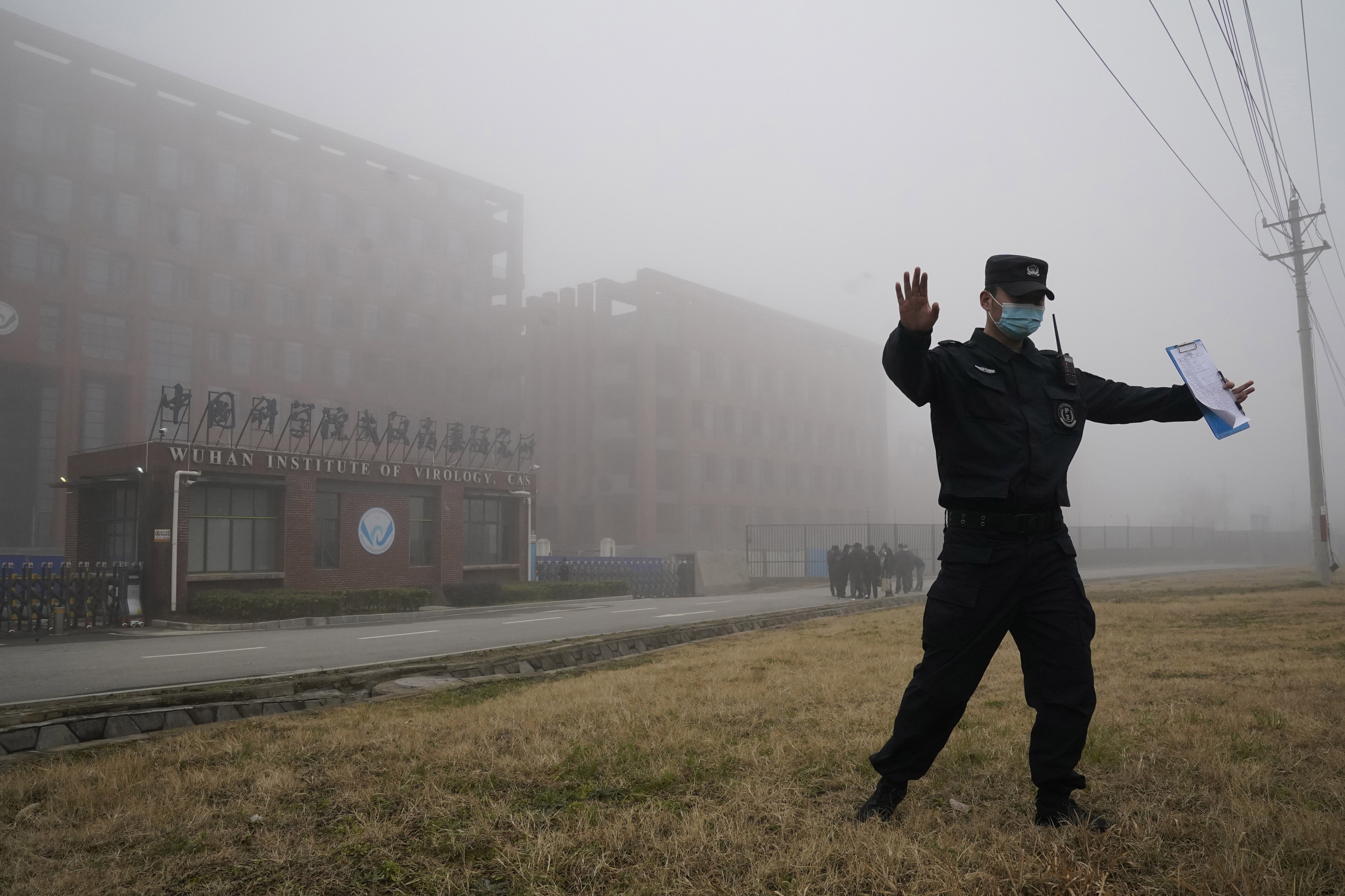 FILE - A security person moves journalists away from the Wuhan Institute of Virology after a World Health Organization team arrived for a field visit in Wuhan in China's Hubei province, Feb. 3, 2021. (AP Photo/Ng Han Guan, File)