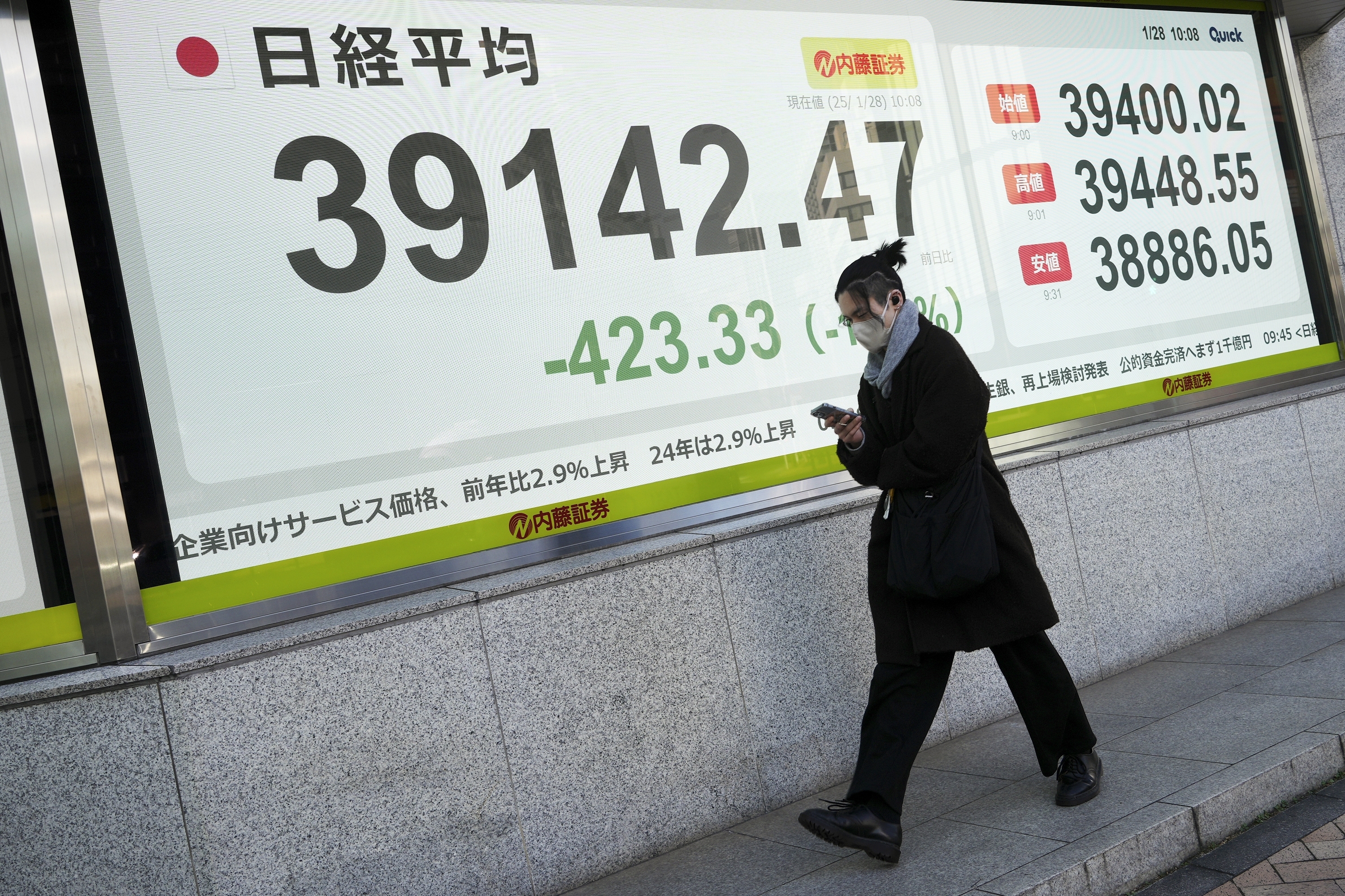 A person walks in front of an electronic stock board showing Japan's Nikkei index at a securities firm Tuesday, Jan. 28, 2025, in Tokyo. (AP Photo/Eugene Hoshiko)