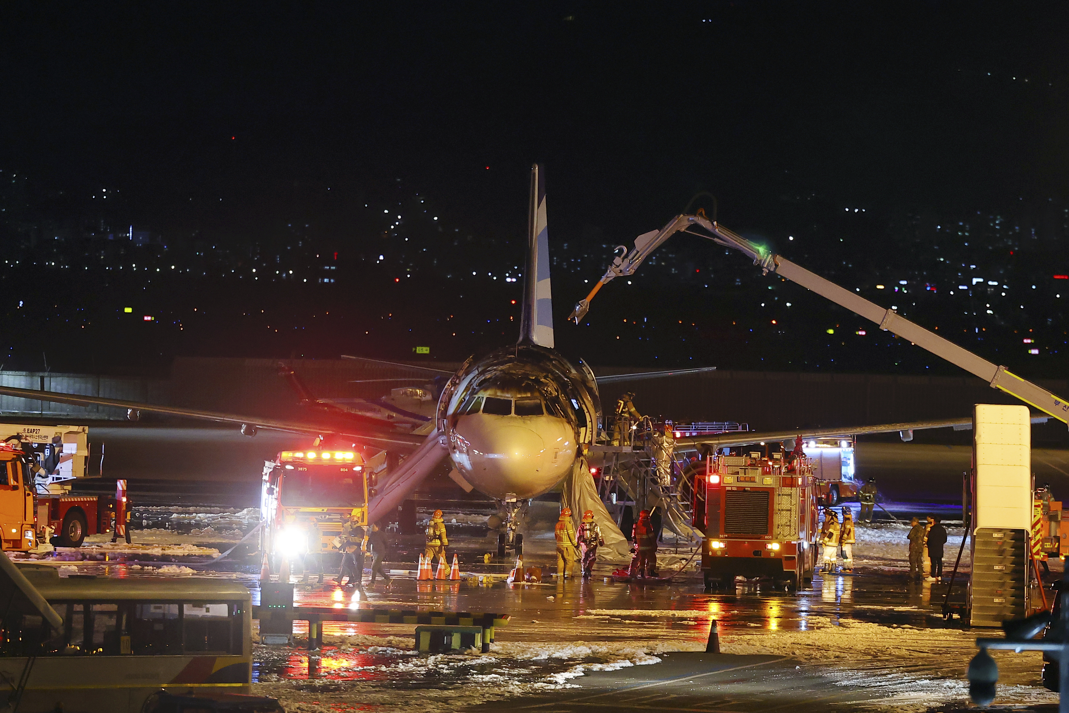 Firefighters work to extinguish a fire on an Air Busan airplane at Gimhae International Airport in Busan, South Korea, Tuesday, Jan. 28, 2025. (Son Hyung-joo/Yonhap via AP)