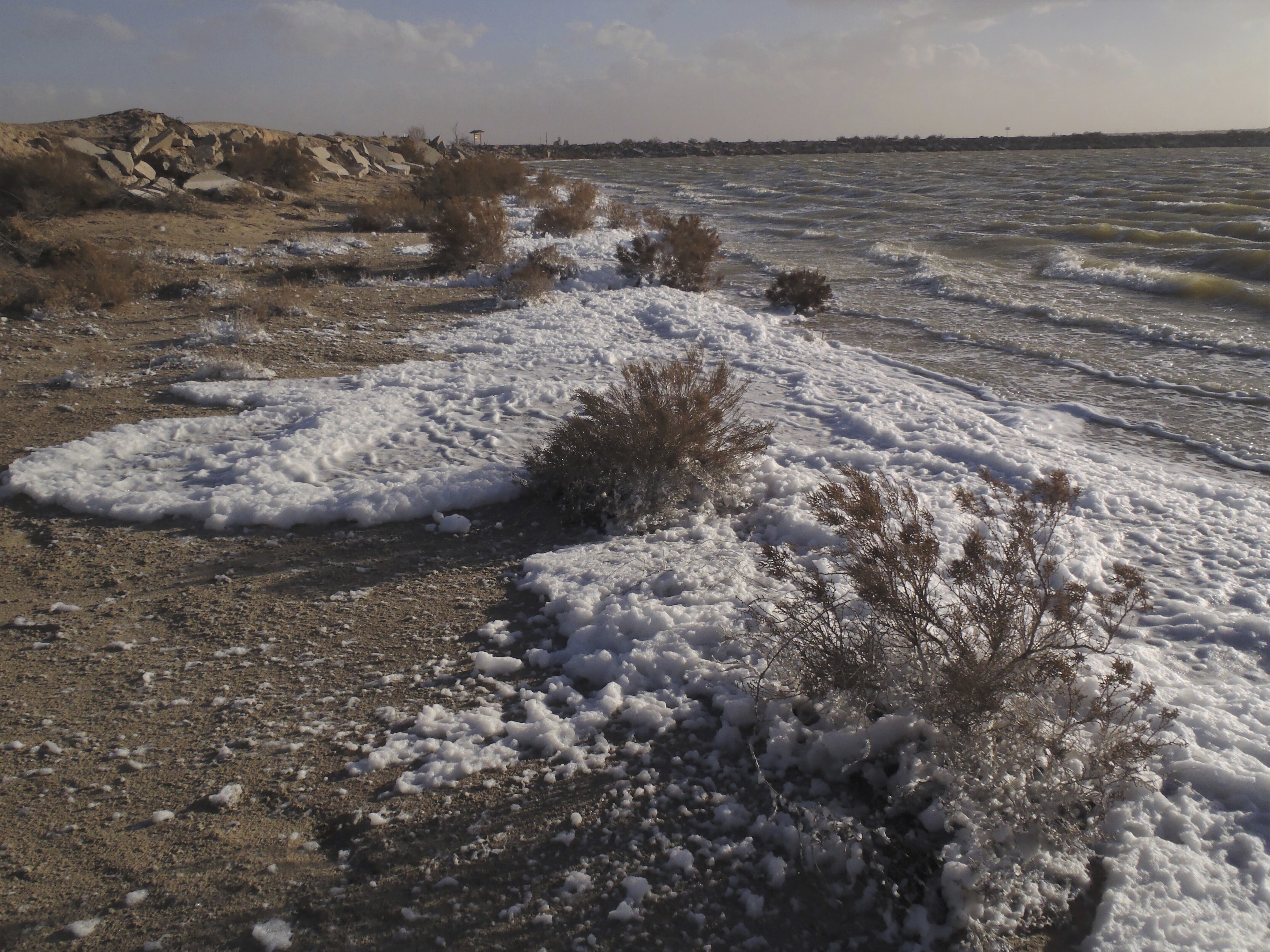 This March 13, 2019, image provided by the New Mexico Environment Department shows foam along the shoreline of Holloman Lake near Alamogordo, N.M. (James Kenney/New Mexico Environment Department via AP)